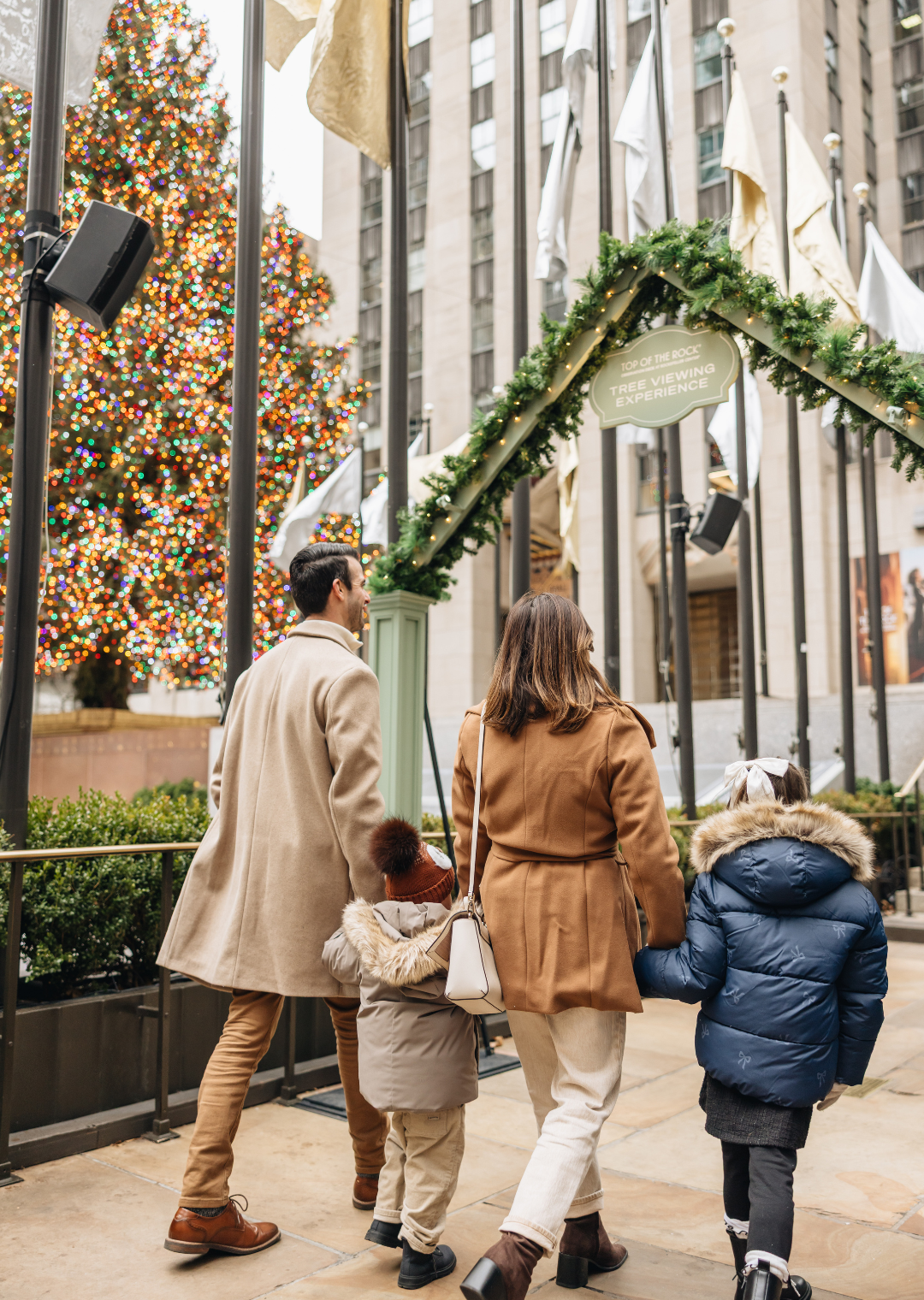 family walking up close by the rockefeller center christmas tree