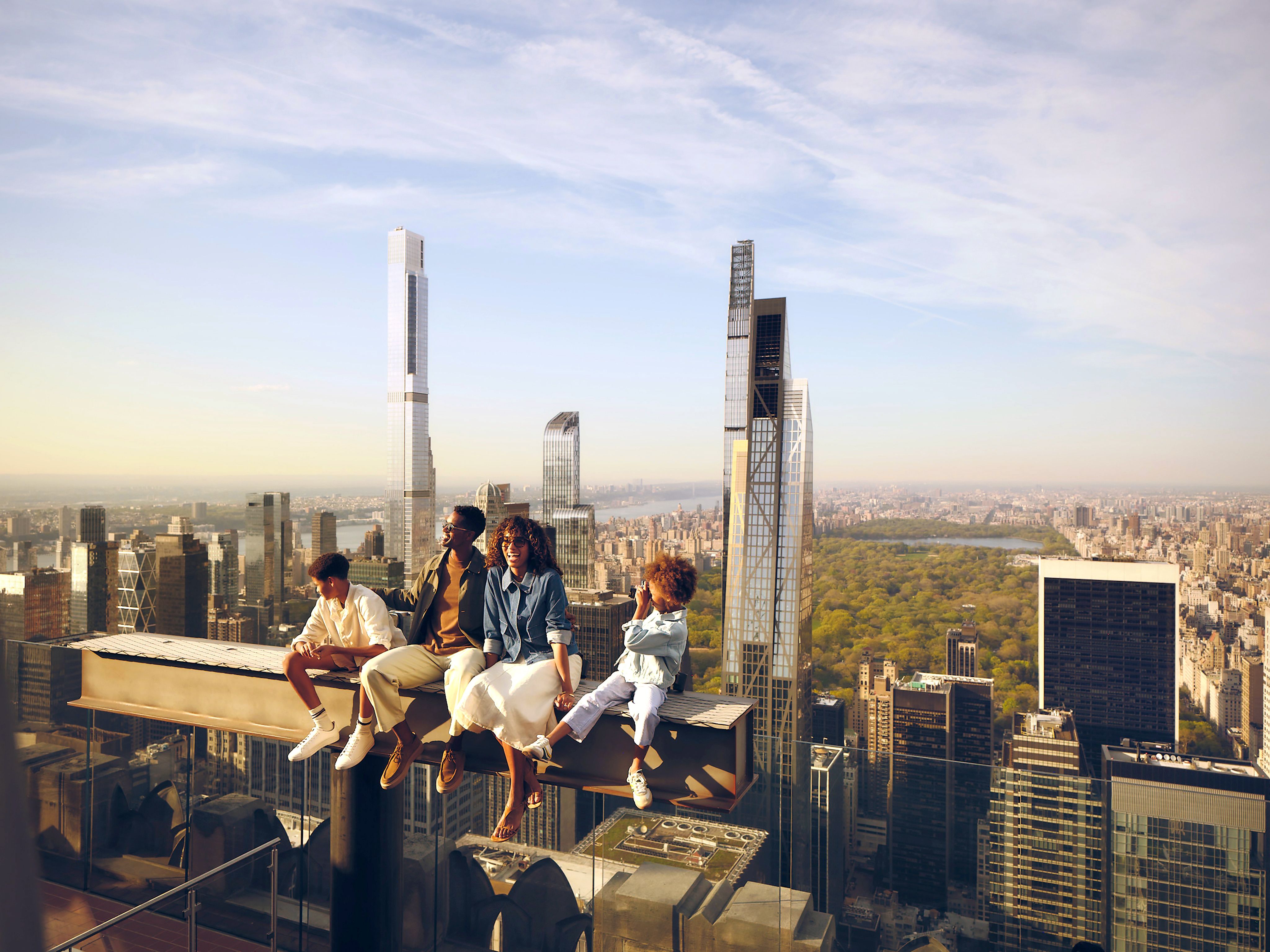 family sitting on The Beam at Top of the Rock