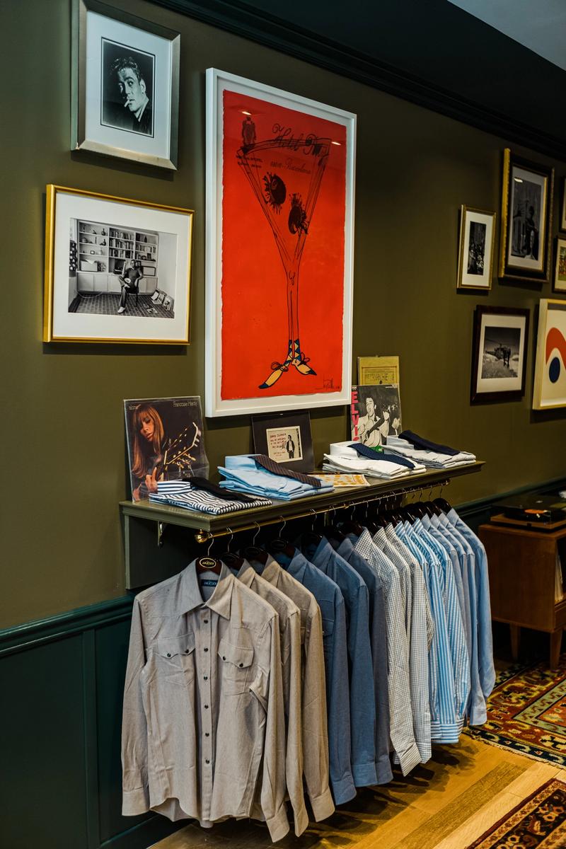 Bespoke men's clothing hanging in a store with vibrant images on the walls