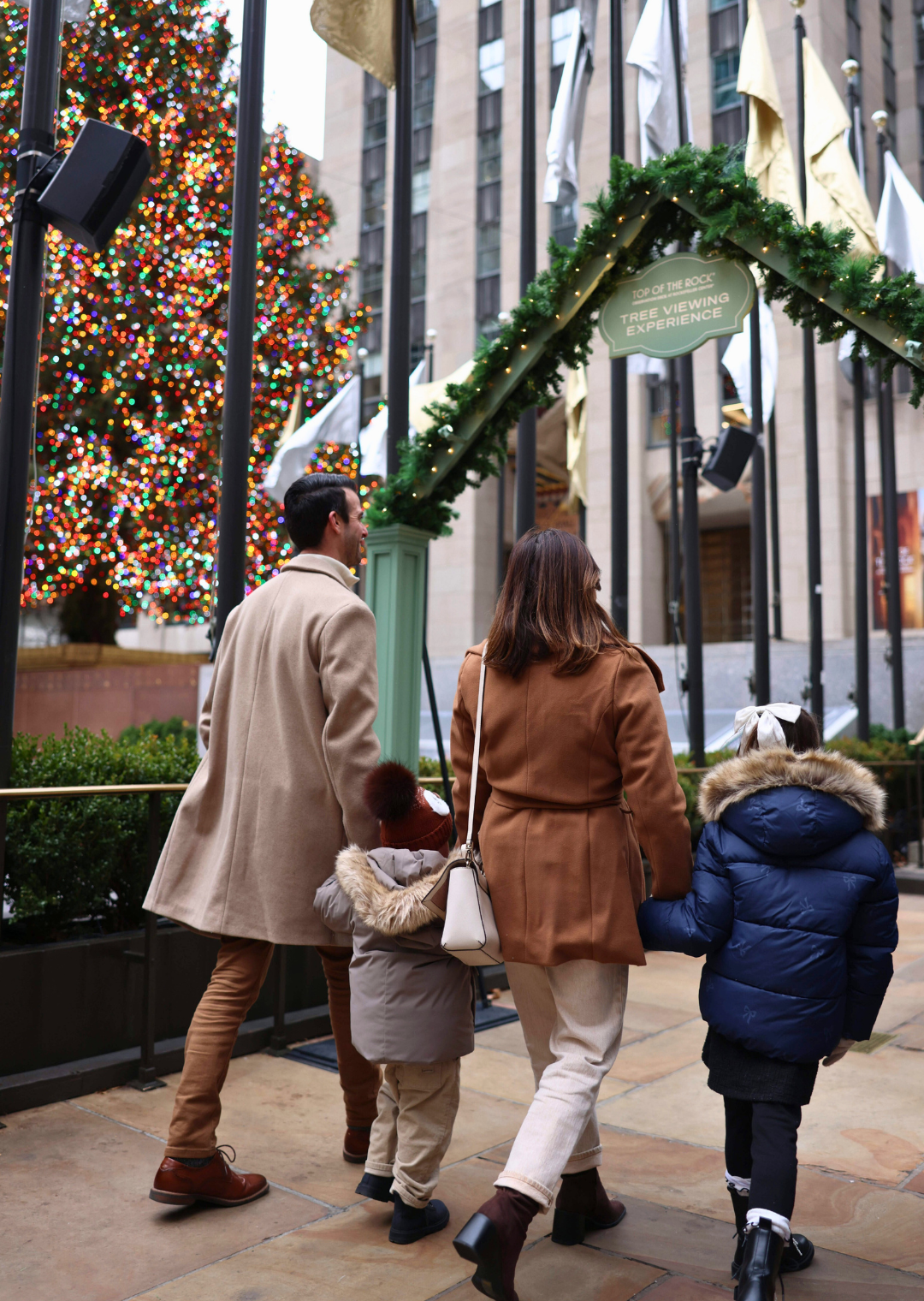 family walking up close by the rockefeller center christmas tree