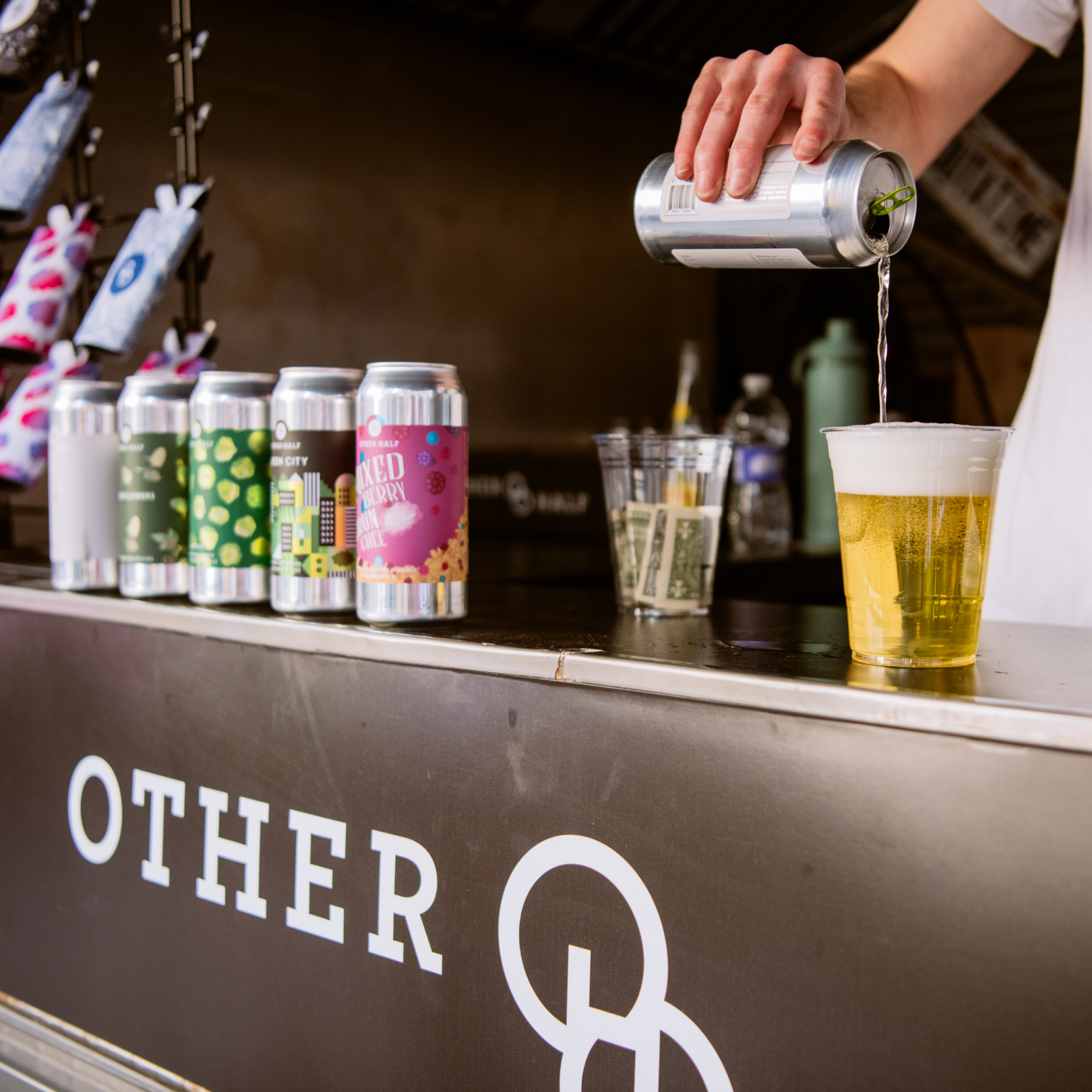 Hand pouring a can of beer into a cup at Other Half Brewing's Rockefeller Center beere garden