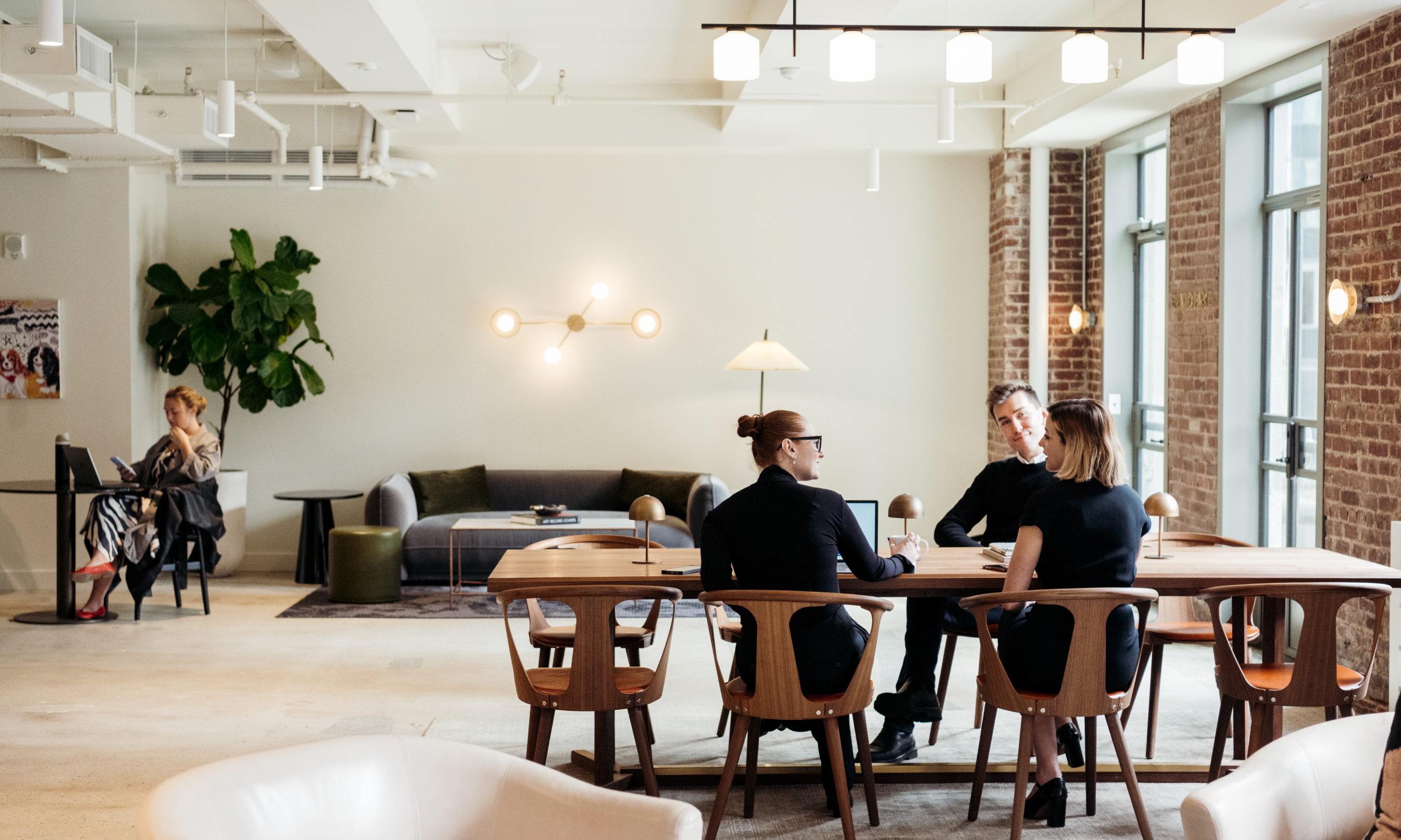 Group of three people working at a table inside the Radio Park West Lounge