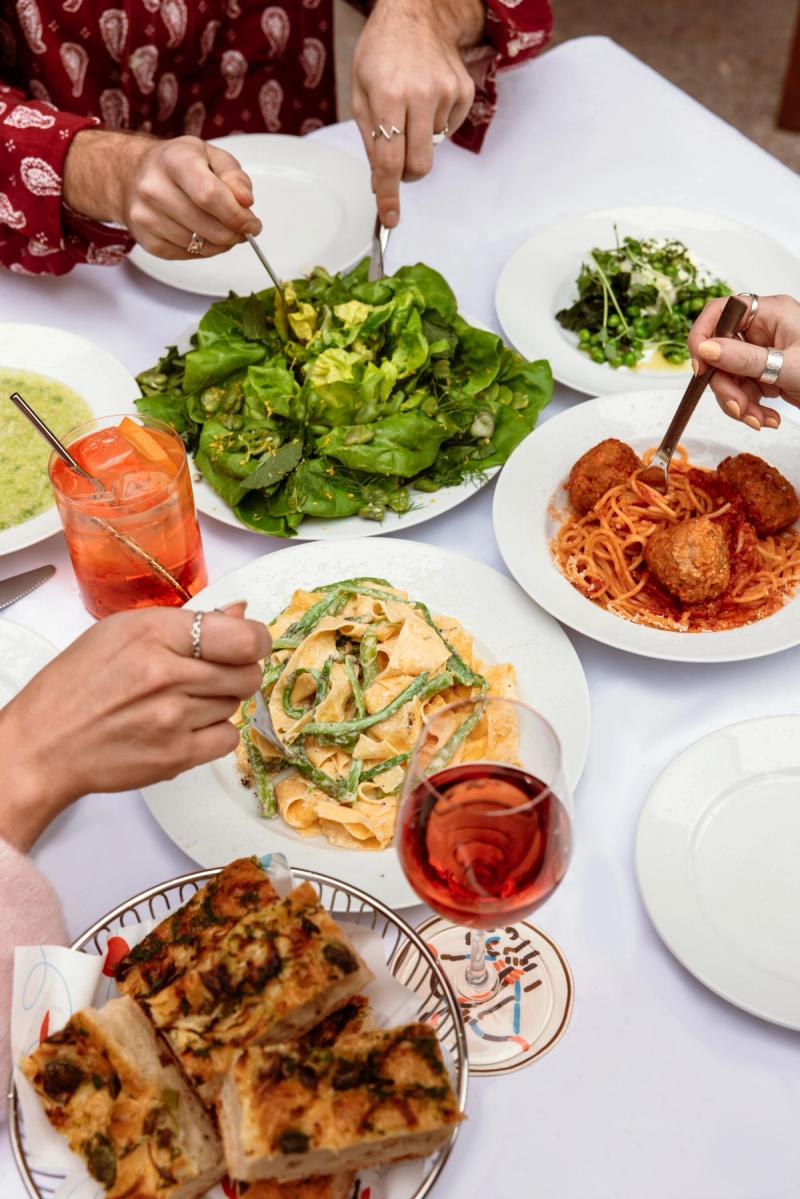 table with pasta, salad, bread, wine and an aperol spritz