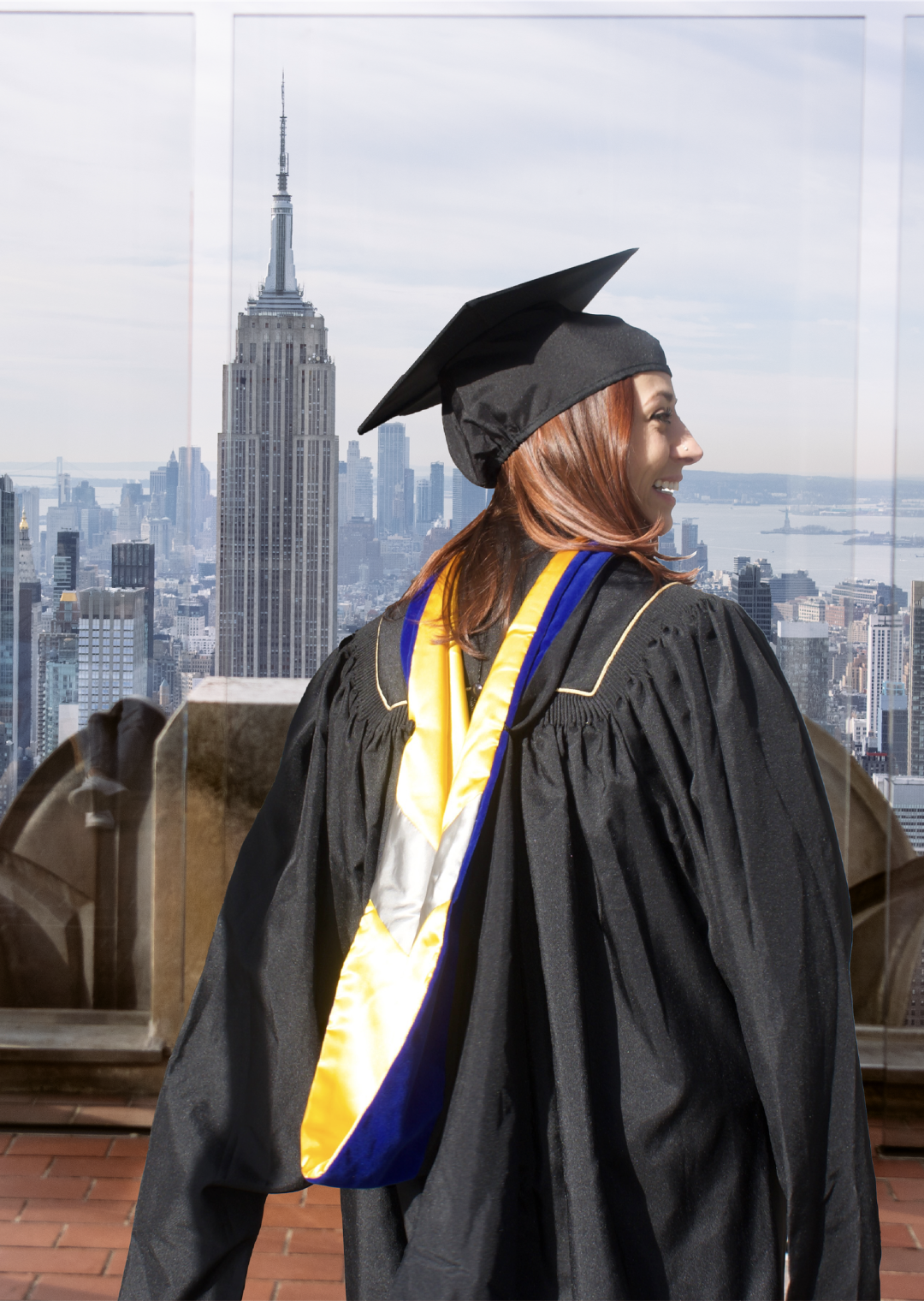 Girl in a graduation cap and gown looking out at the skyline at Top of the Rock