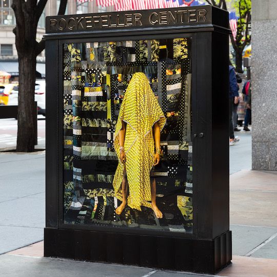 Poster of a person covered in a yellow quilt for artist Basil Kincaid's Art in Focus exhibit at Rockefeller Center