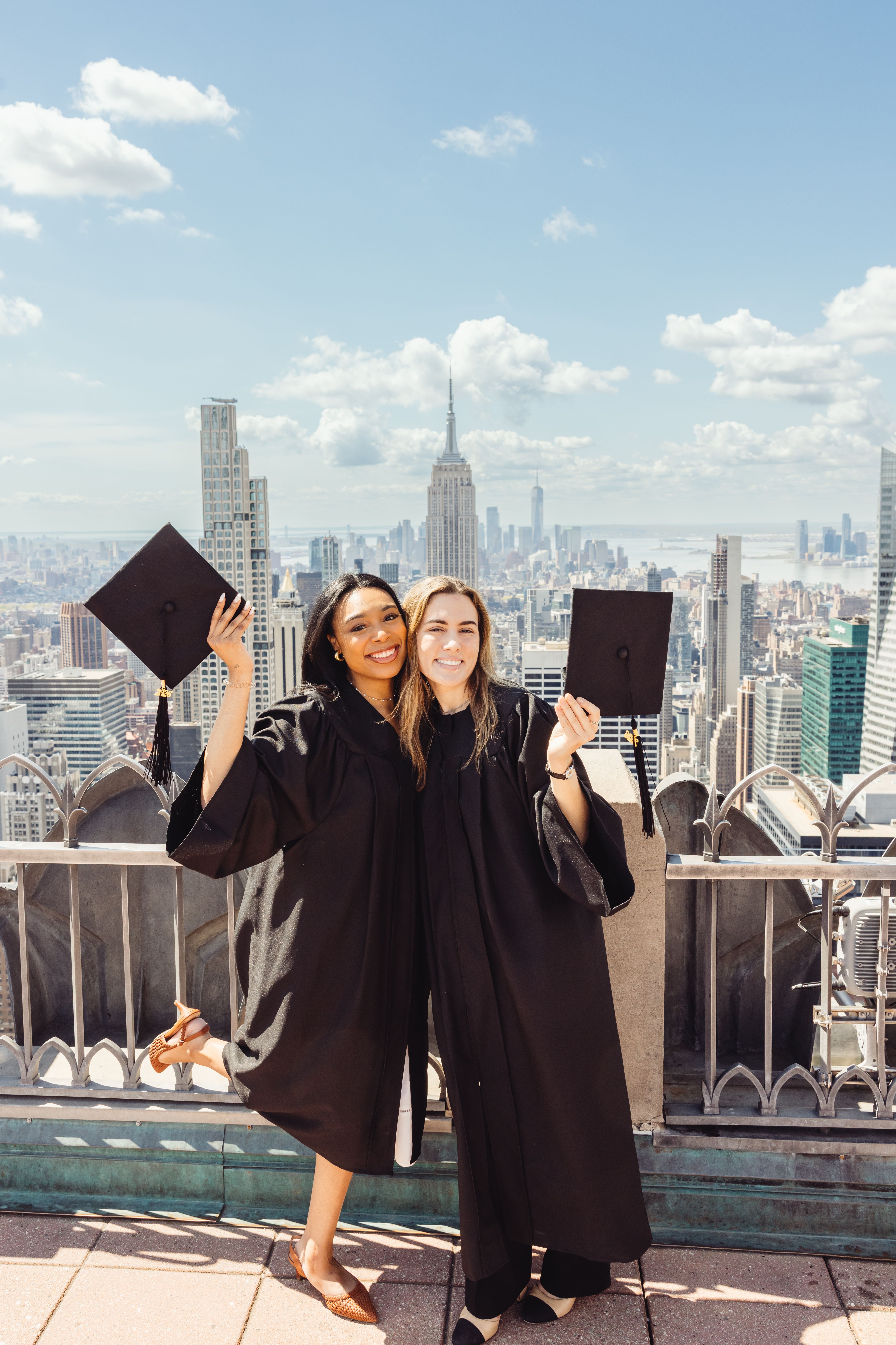 two graduates smiling at top of the rock