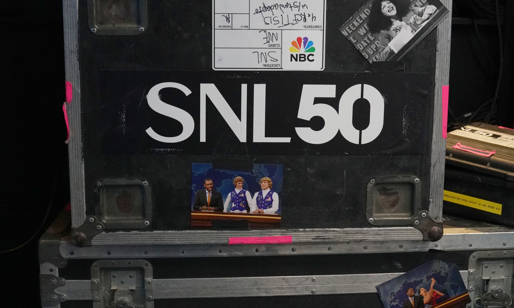 A black case with SNL50 stickers and photos of past sketches at the 'Live from New York: The SNL50 Experience'