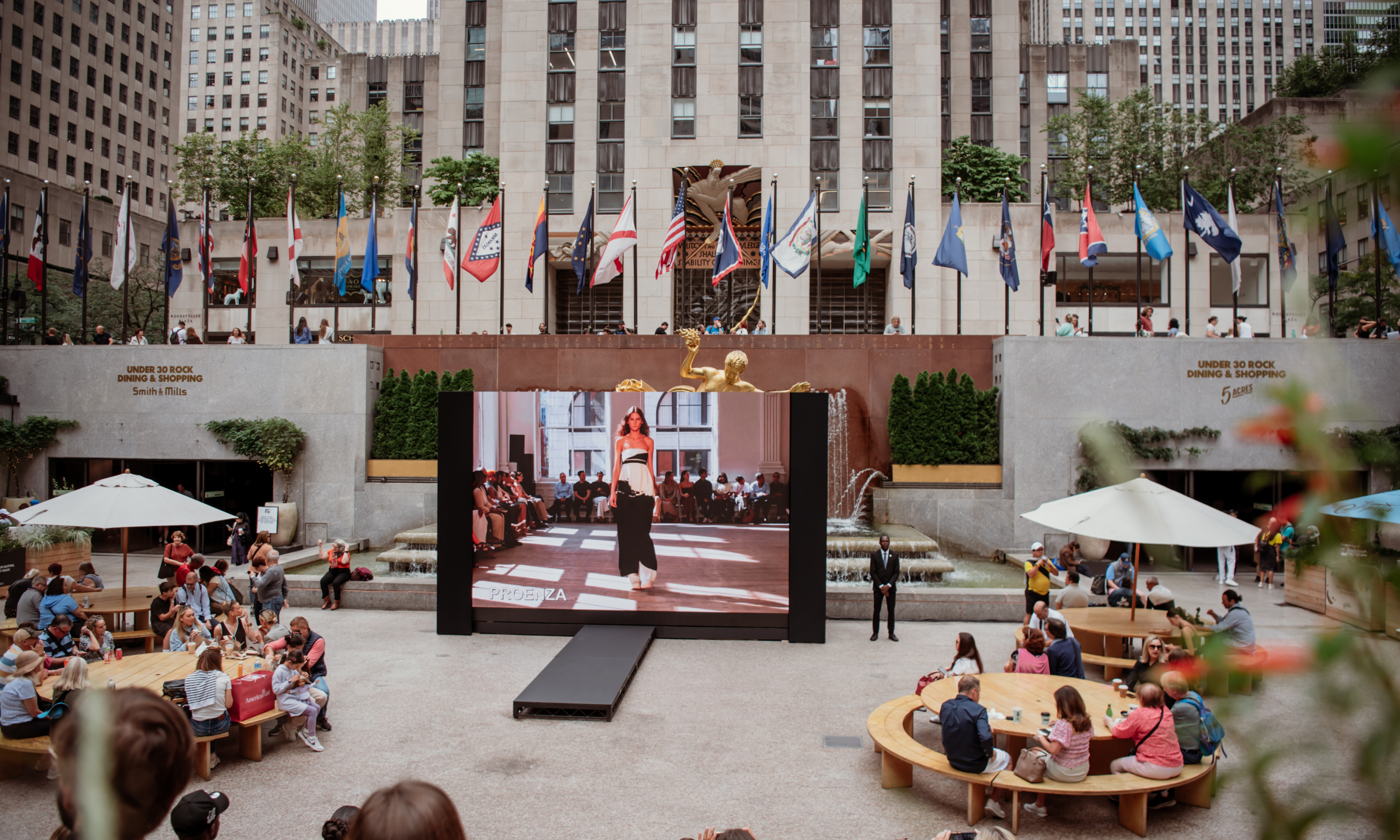People sitting at tables and watching live screenings of fashion shows at The Rink
