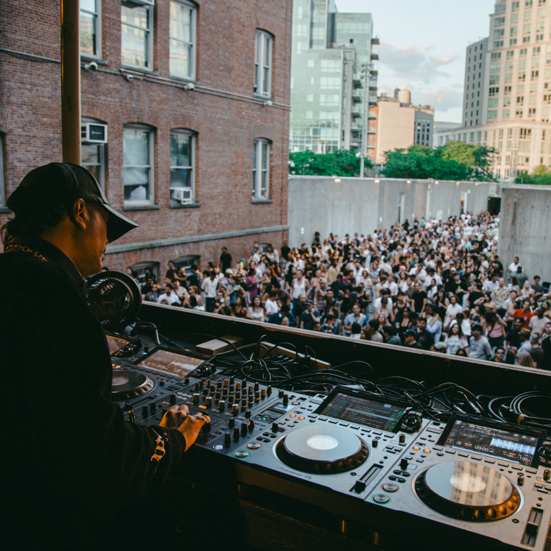 A DJ performs in front of a large crowd as part of MoMA PS1’s Warm Up concert series