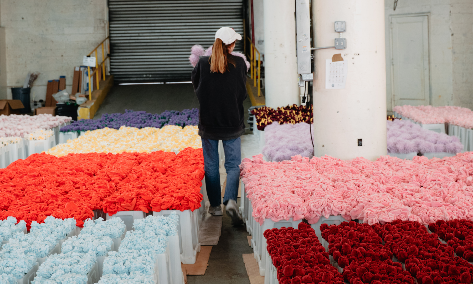 Cj Hendry walking through a warehouse filled with her plush flower designs
