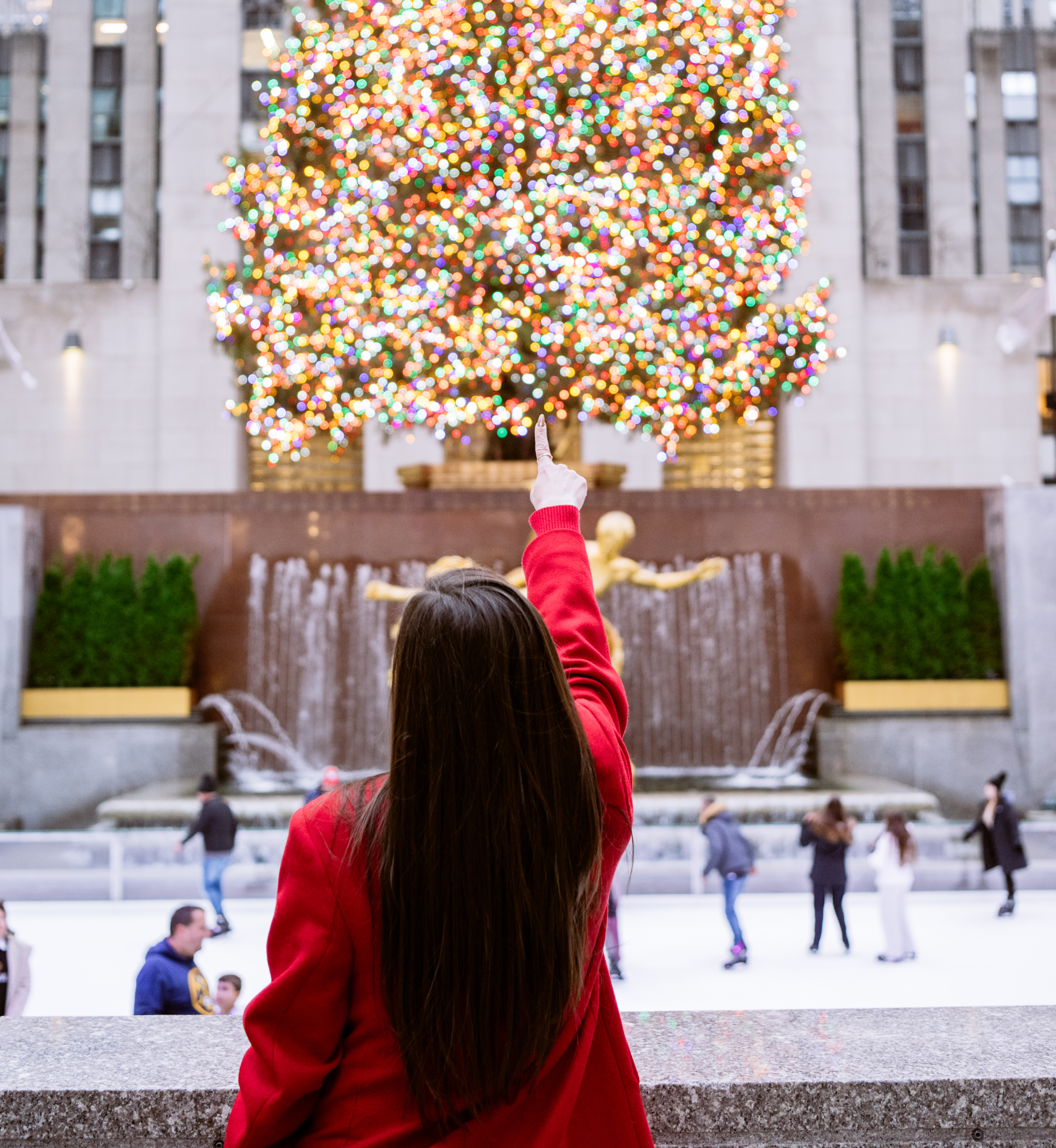 A woman pointing at the Rockefeller Center Christmas Tree