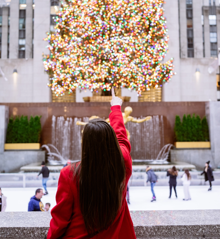 A woman pointing at the Rockefeller Center Christmas Tree