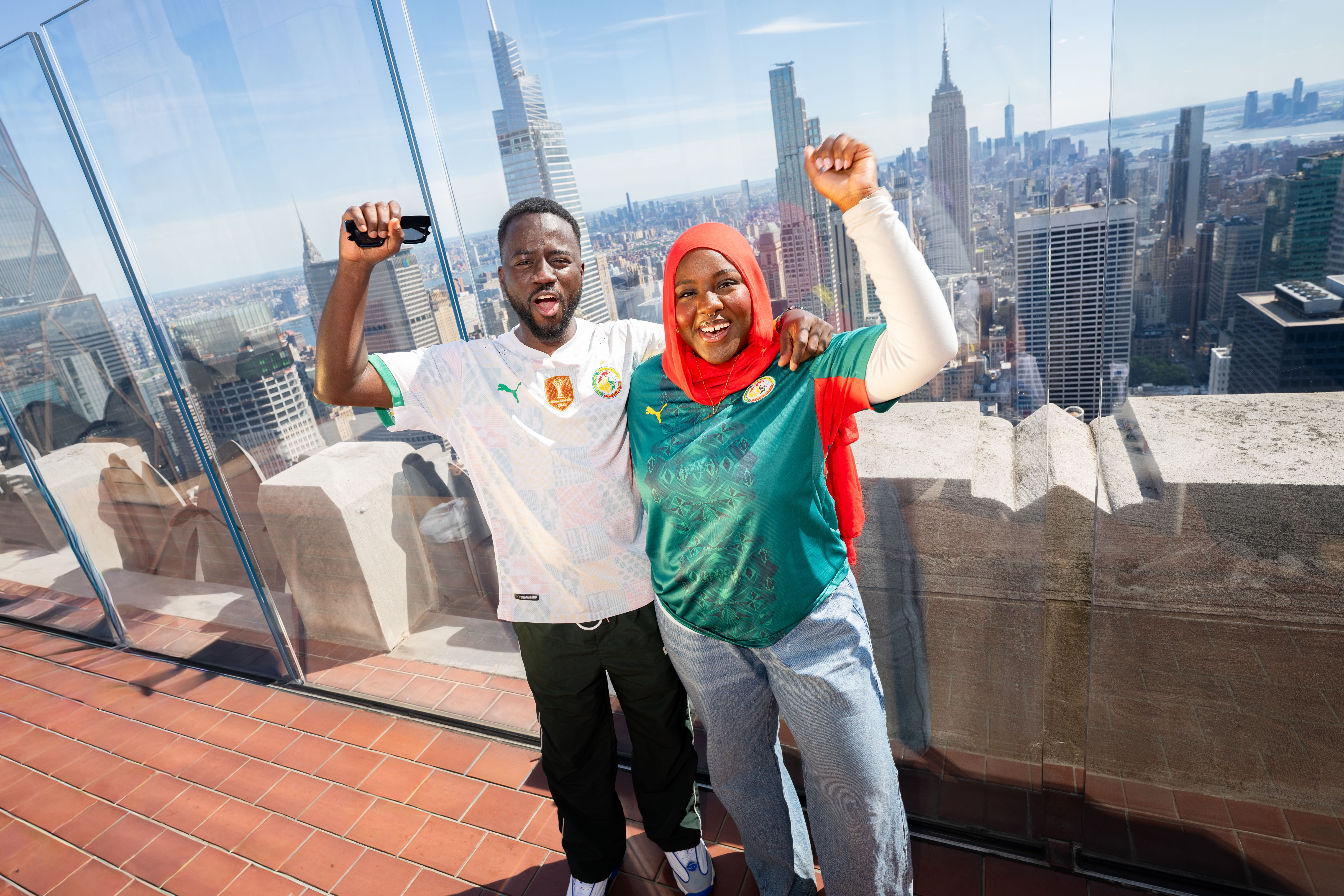 a man and a woman cheering on their soccer team at top of the rock