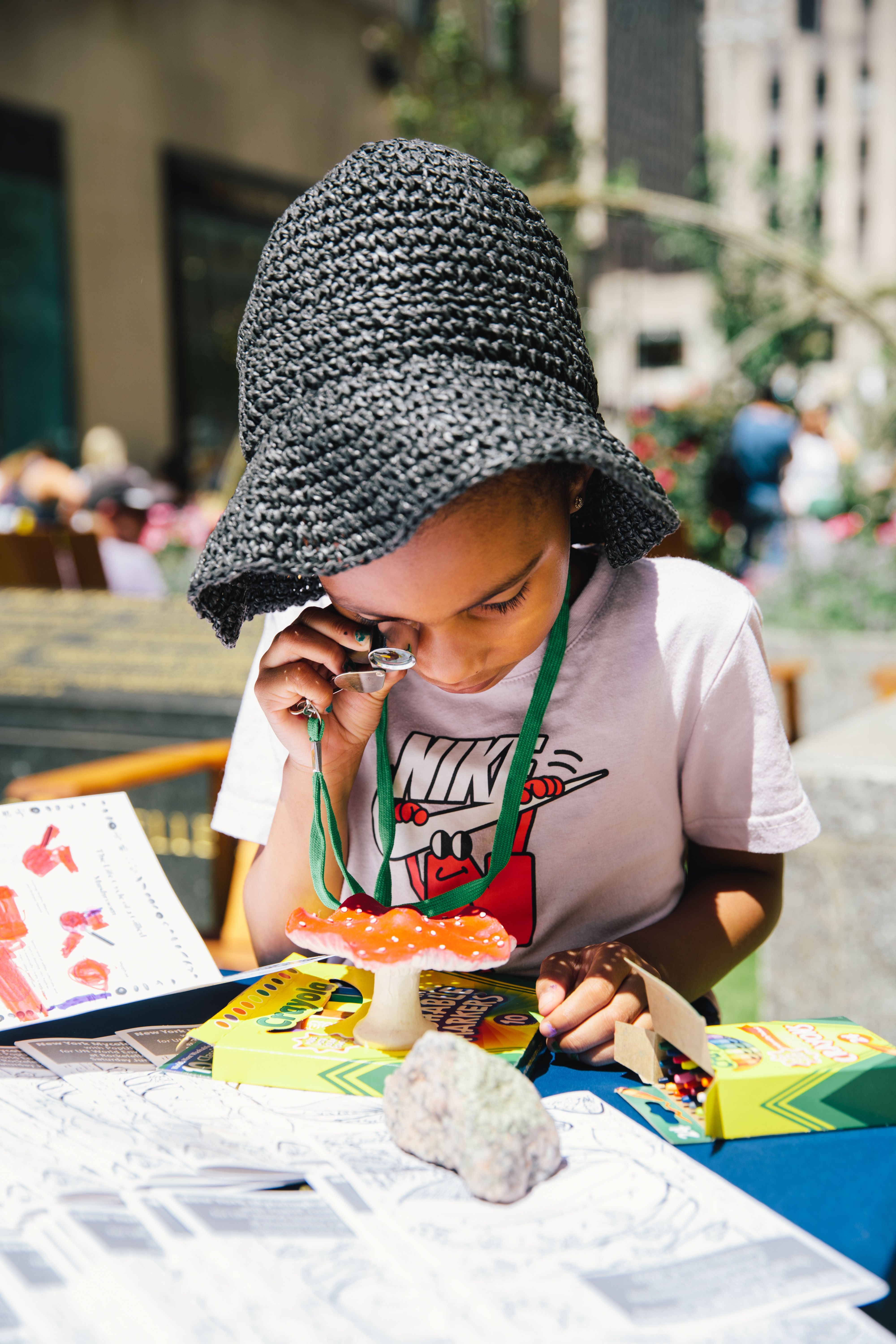 Girl Wearing a hat looking at a mushroom