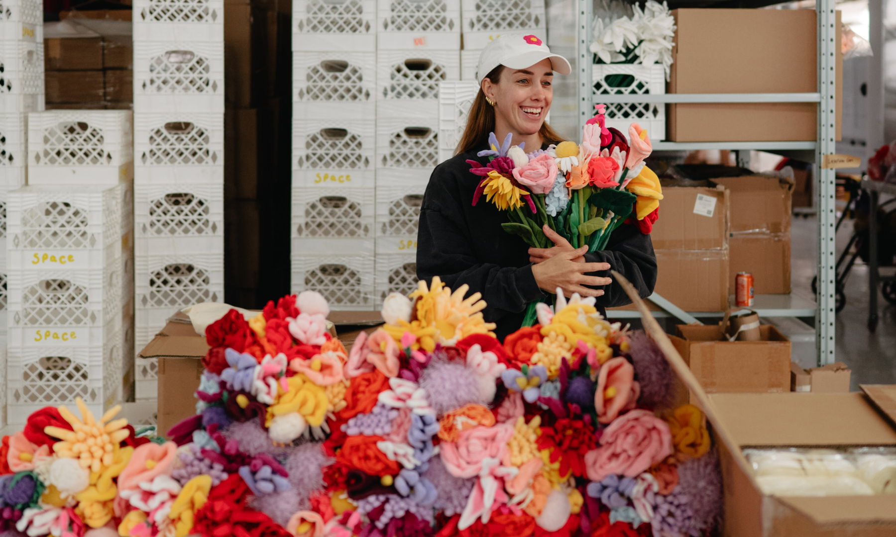 Artist Cj Hendry holding a bouquet of plush flowers