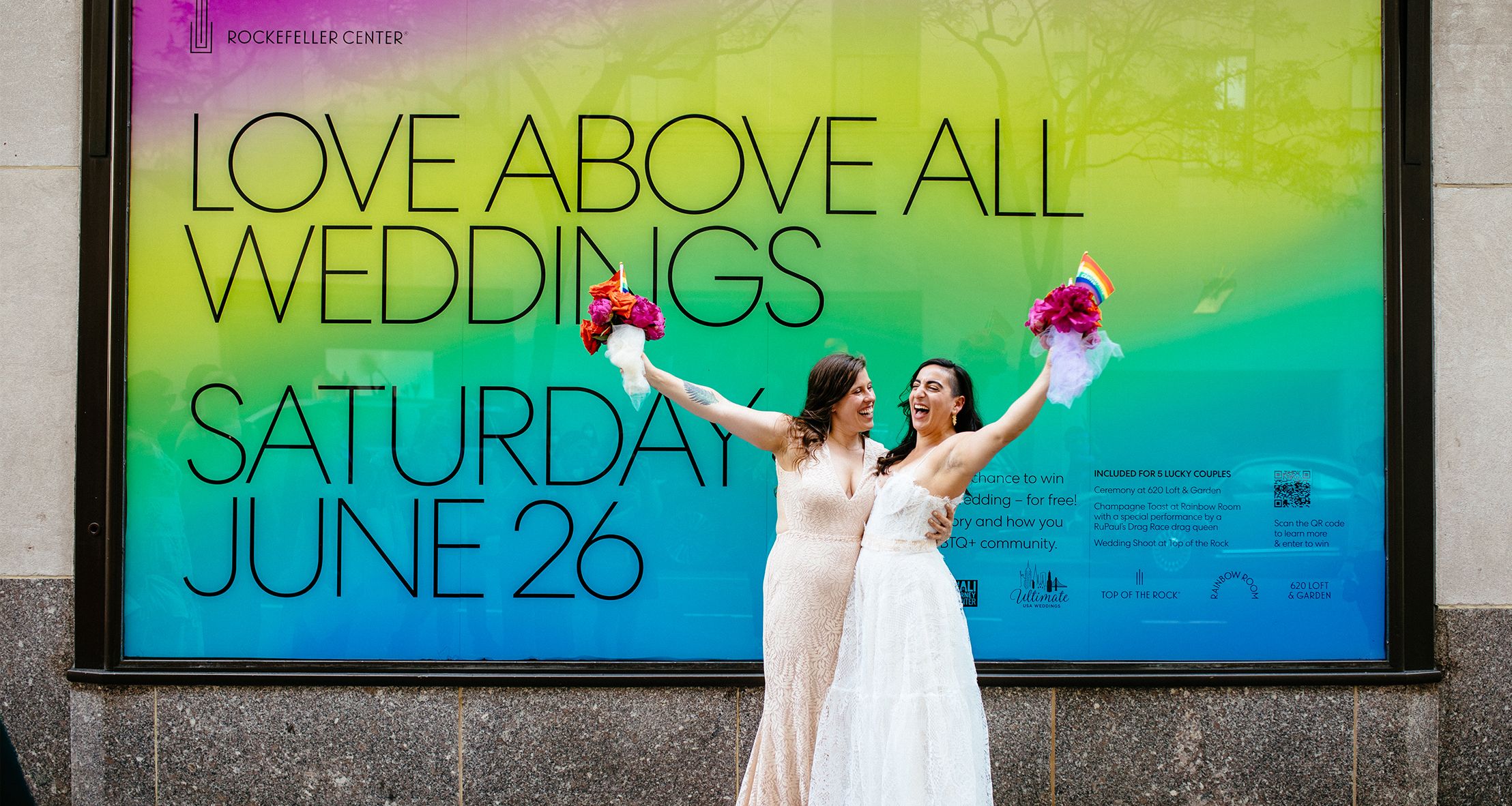 Chelsea and Mia posing in front of the Love Above All sign on the plaza