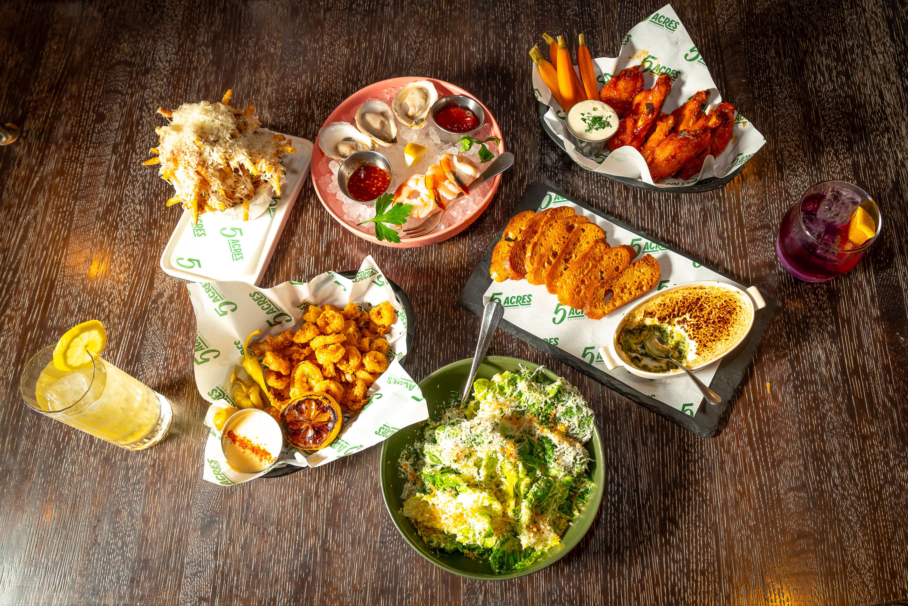 Plate of various wings, sandwiches, and salads from 5 Acres