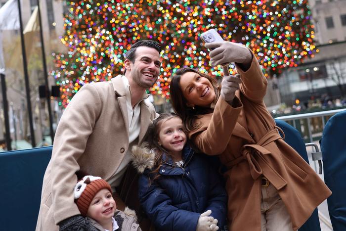 family taking a selfie in front of the rockefeller center christmas tree