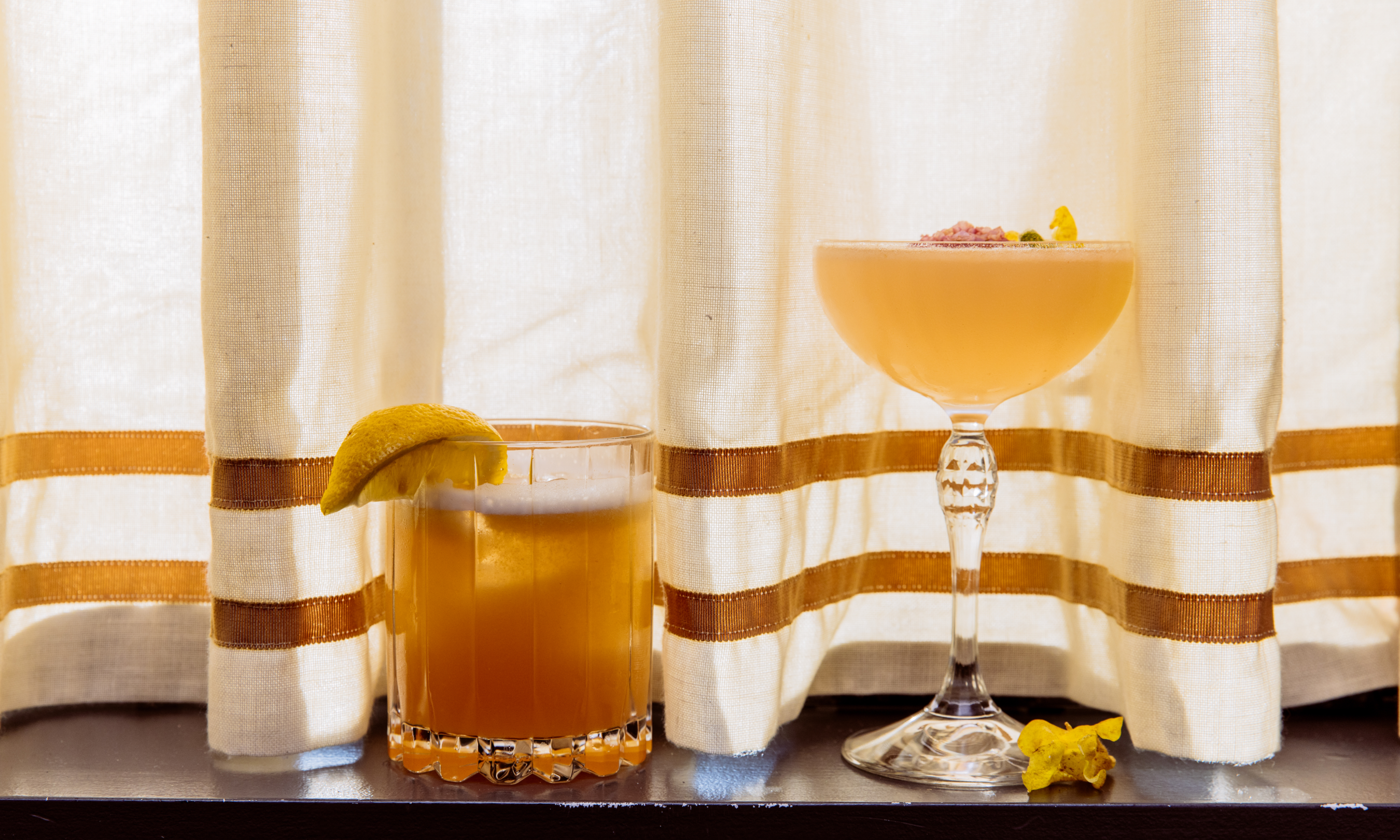 Two Pebble Bar cocktails resting on a window ledge