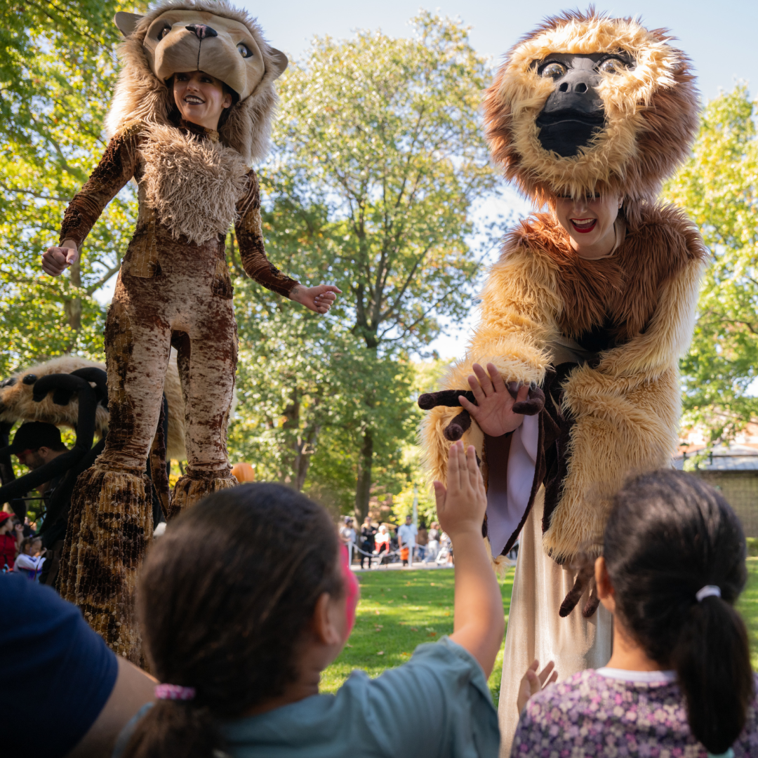 Two women dressed in animal costumes greeting a group of children at the Bronx Zoo
