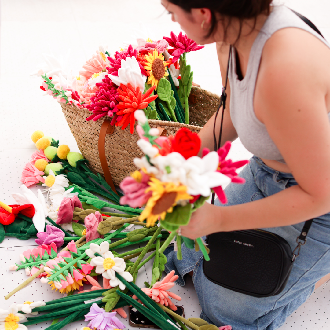 A person placing fake flowers into a basket at artist Cj Hendry's Flower Market