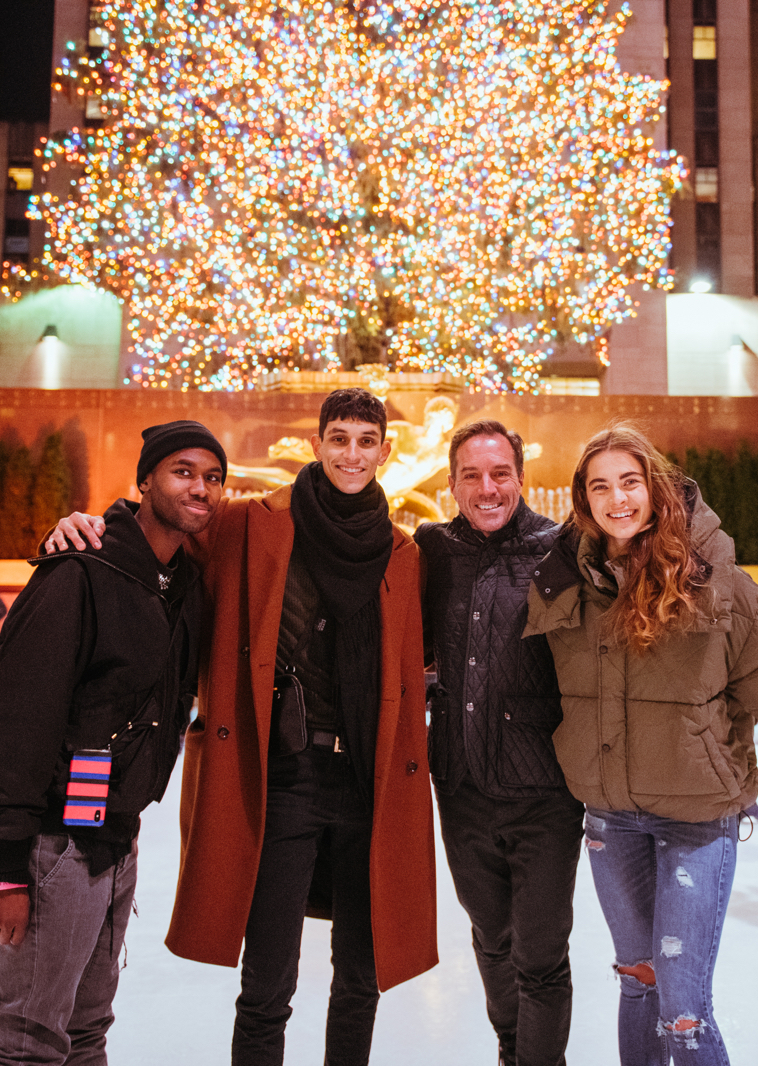 a group of smiling people on the rink at rockefeller center