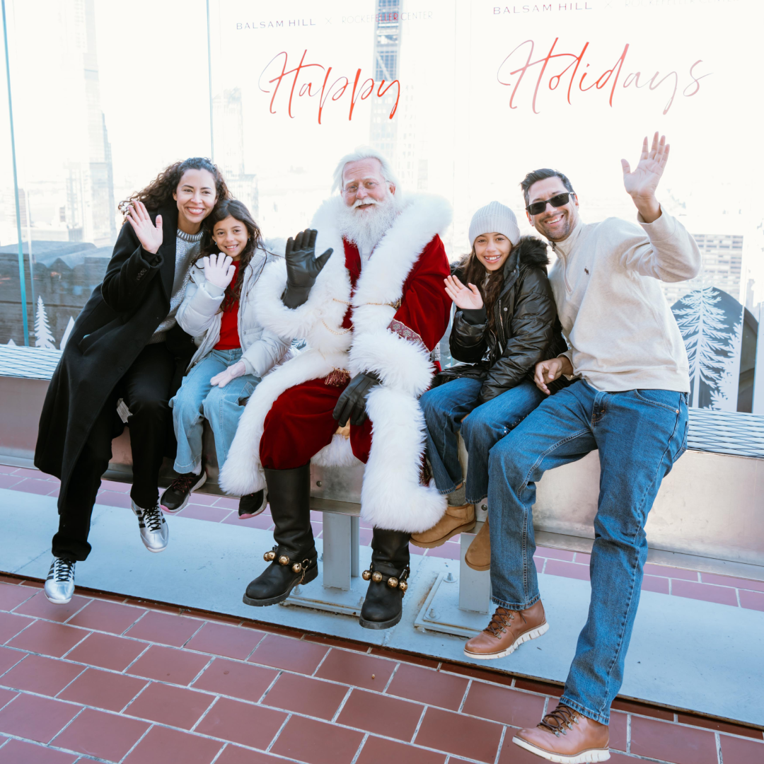 Family of four and Santa Claus posing for a photo on The Beam at Top of the Rock