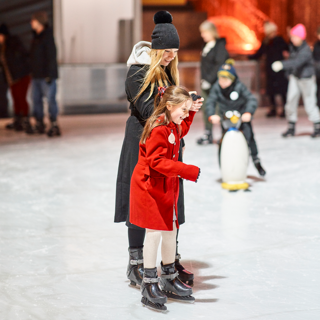 A woman and child ice skating at The Rink at Rockefeller Center