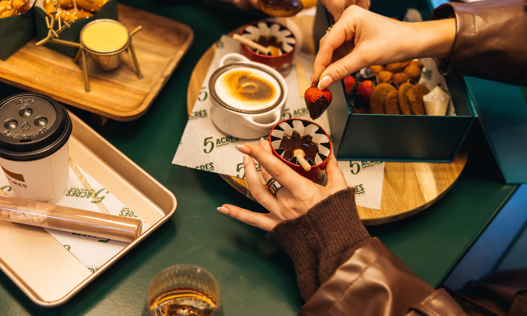 A person dipping a strawberry in a bowl of chocolate inside the Apres Skate Chalets