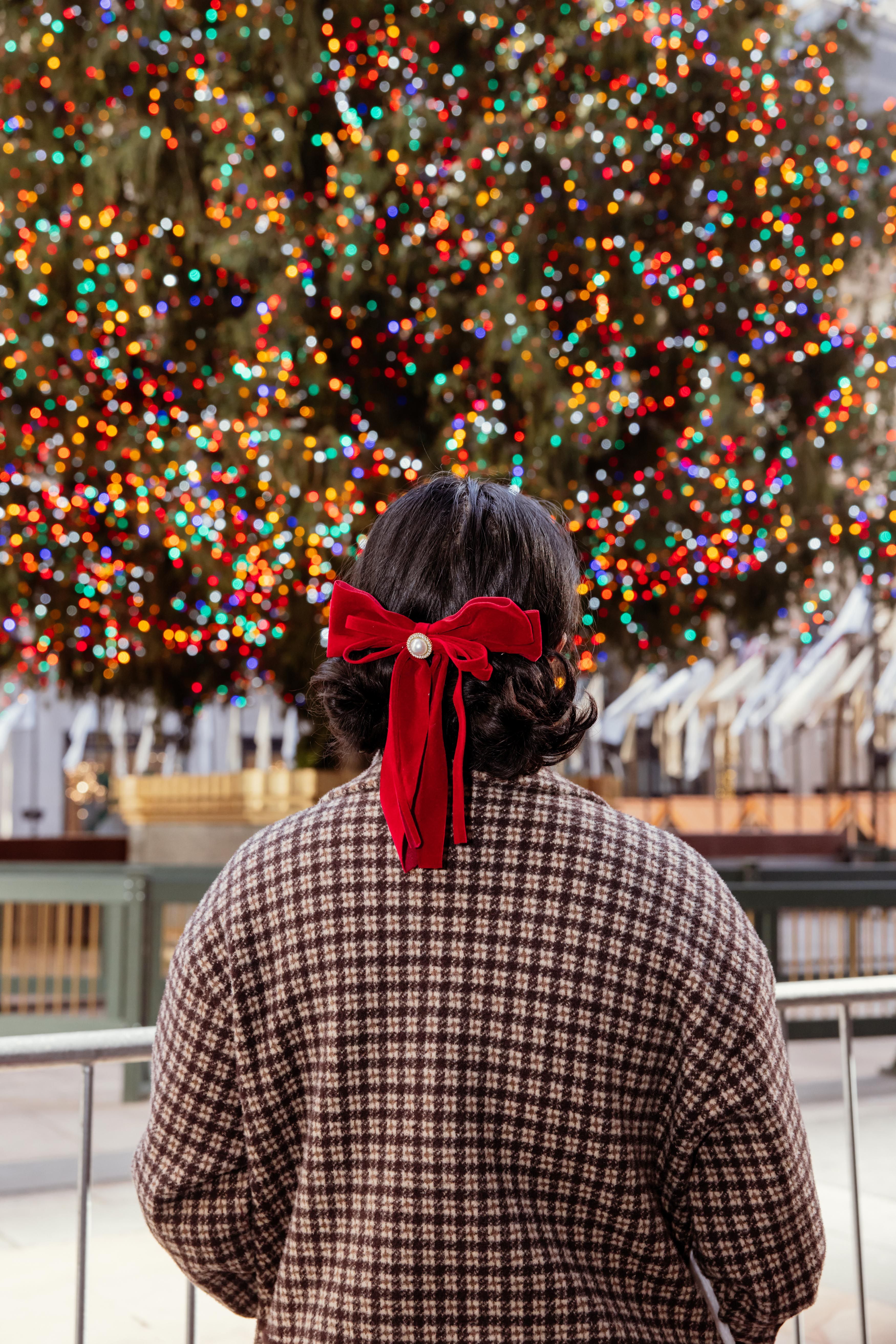 woman with red bow in front of the christmas tree