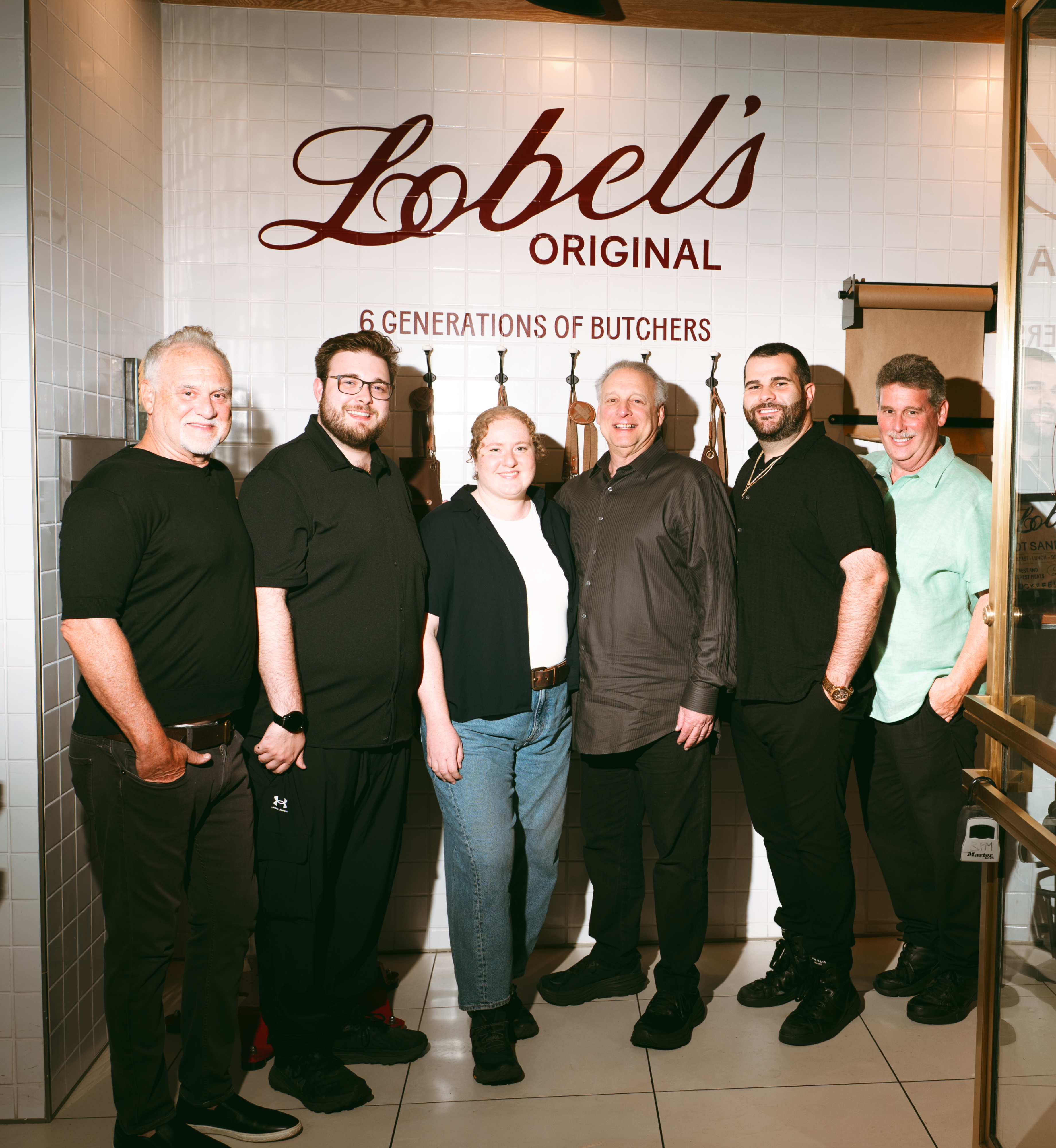 Six members of the Lobel family pose for a photo inside Lobel's Original at Rockefeller Center