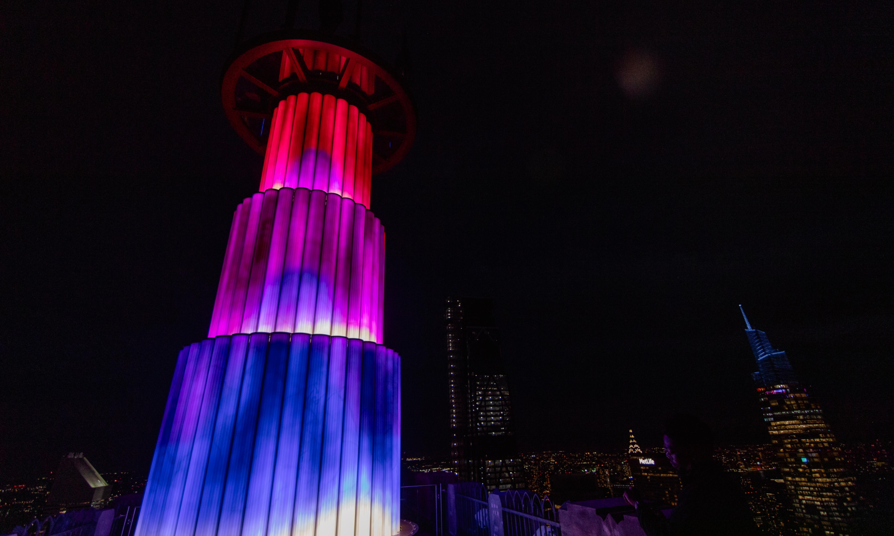 SKYLIFT's illuminated base during the evening light show at Top of the Rock