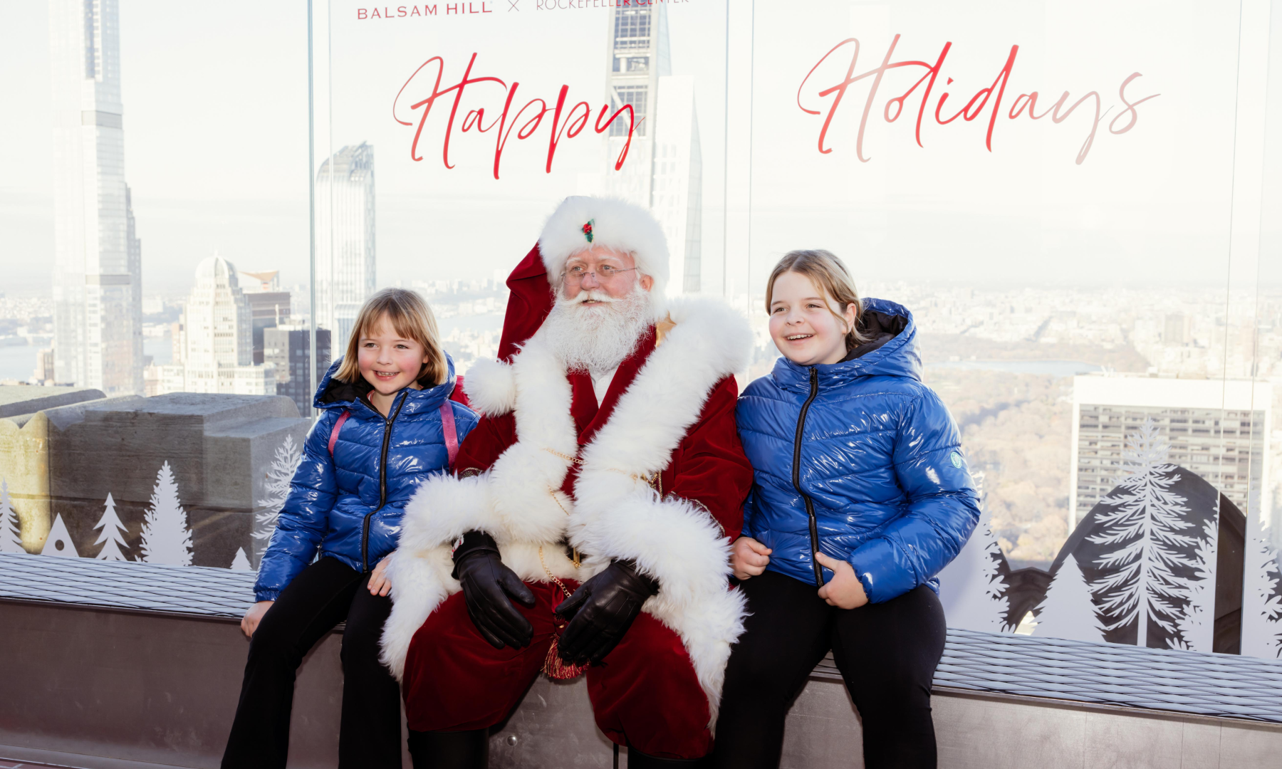 Two children taking a photo with Santa on The Beam at Top of the Rock