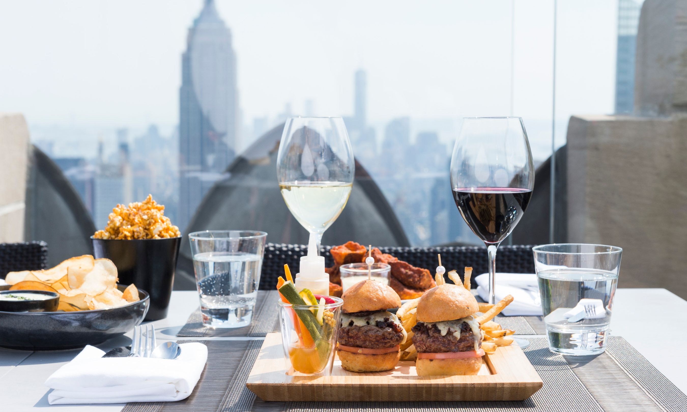 Glasses of wine and plates of food on a table on Bar SixtyFive's outdoor terrace