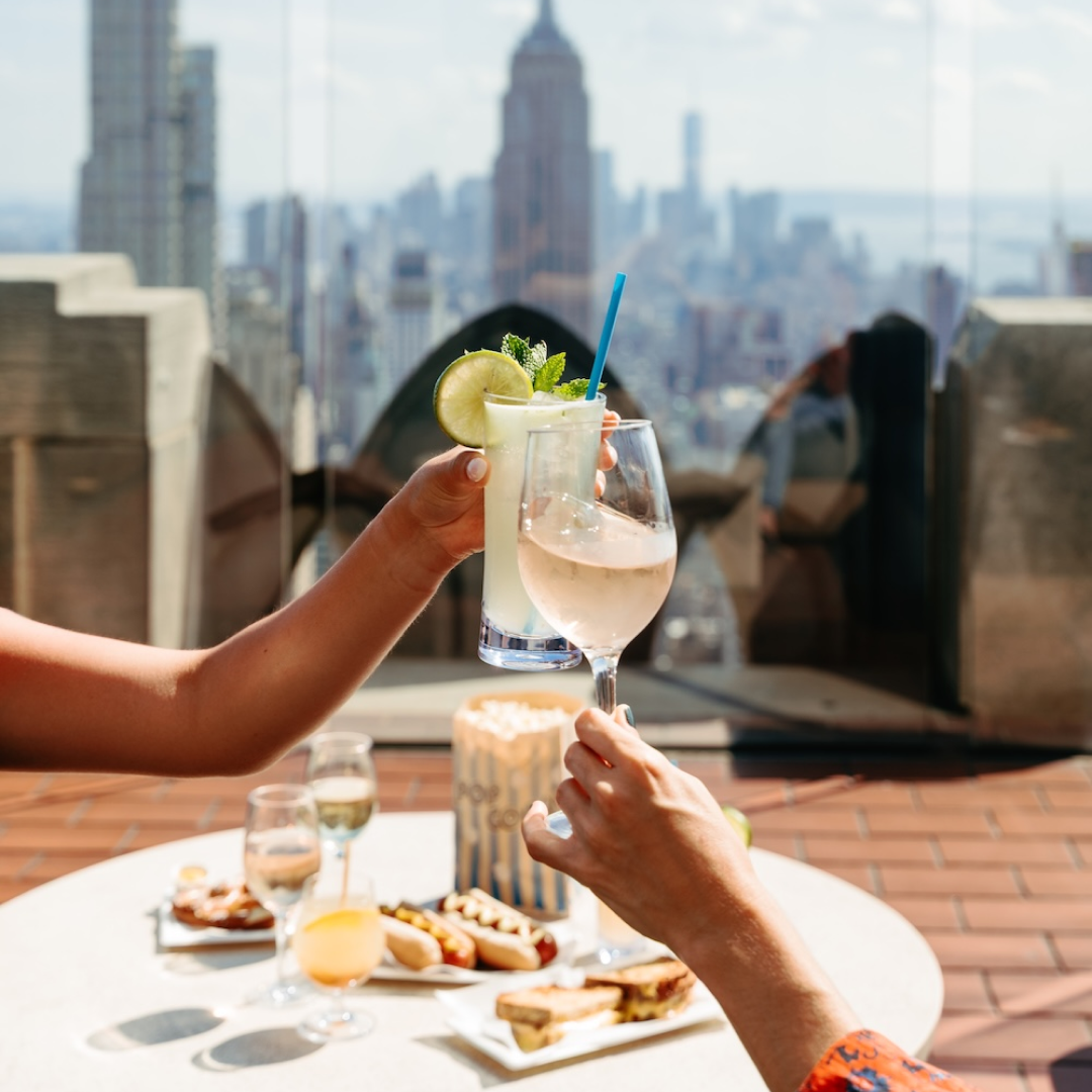 Two hands clinking glasses at The Weather Room at Top of the Rock