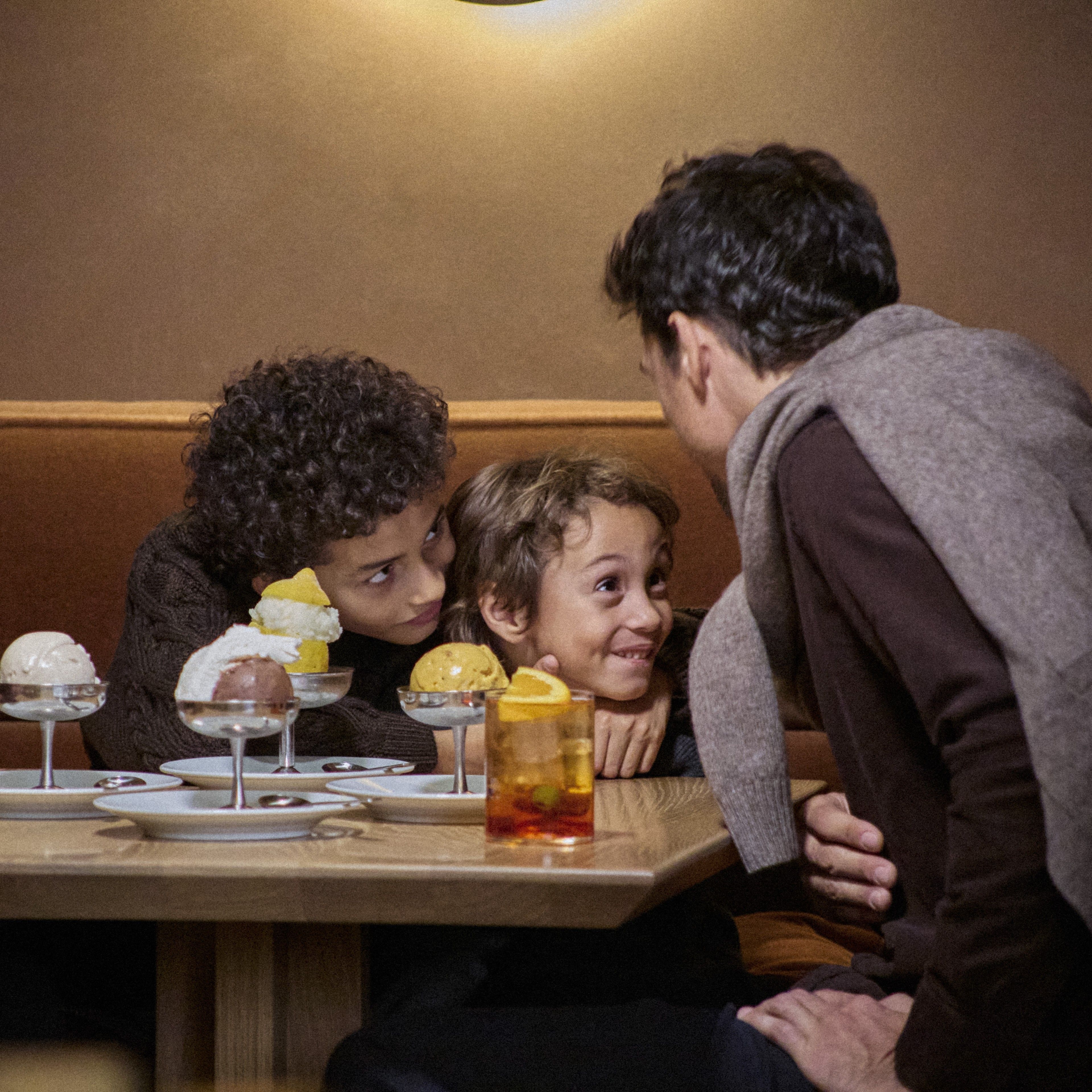 two young boys smiling a their dad at a table at Jupiter with ice cream in front of them