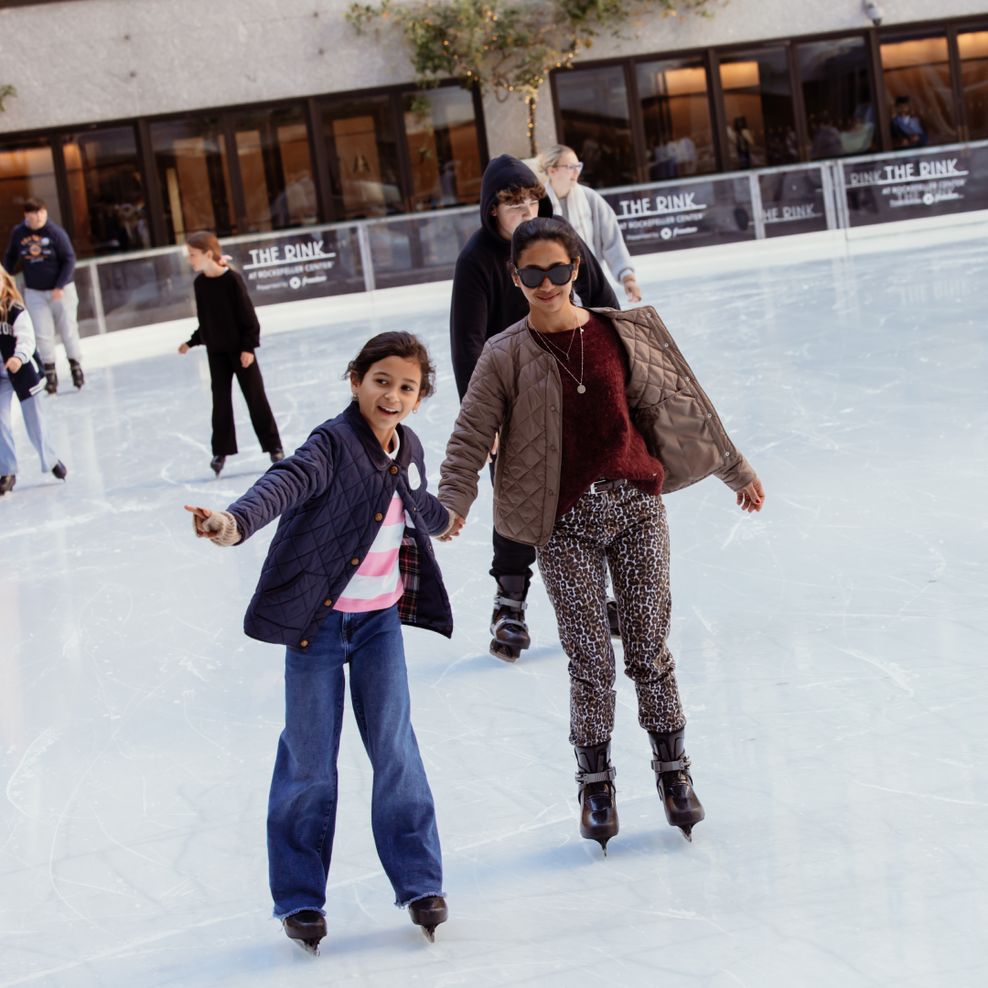 A mother and child ice skating at The Rink at Rockefeller Center