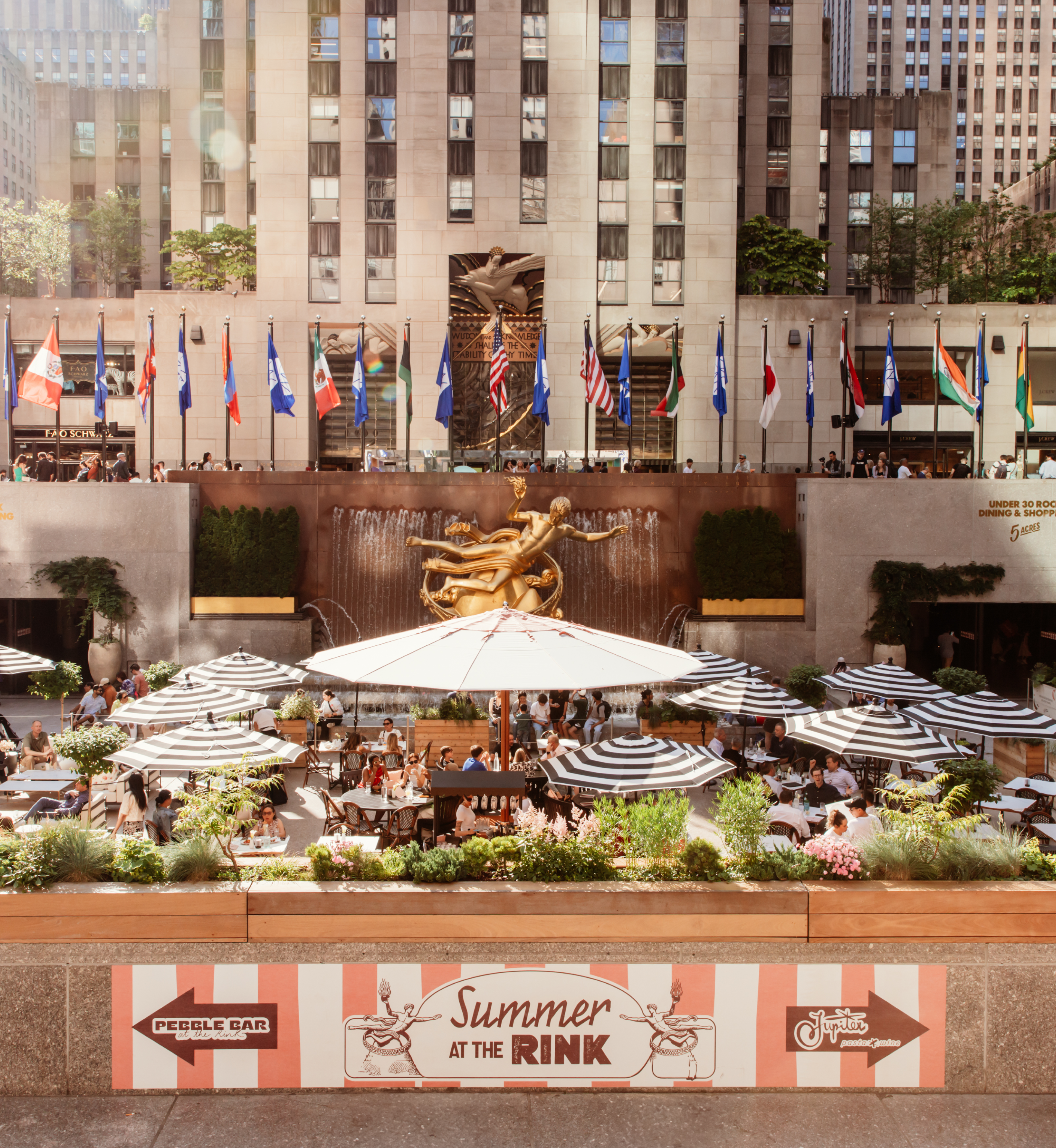Groups of people sitting under umbrellas as part of Rockefeller Center's Summer at The Rink