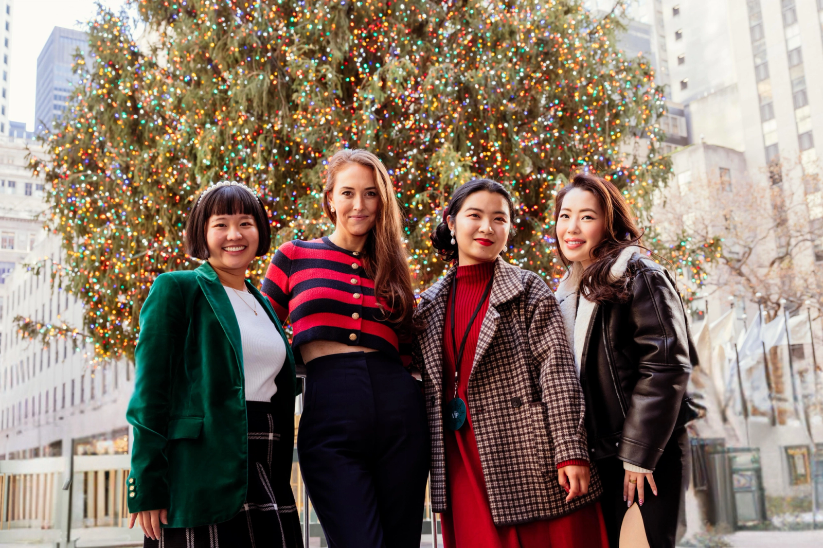 group of smiling women in front of rockefeller center christmas tree
