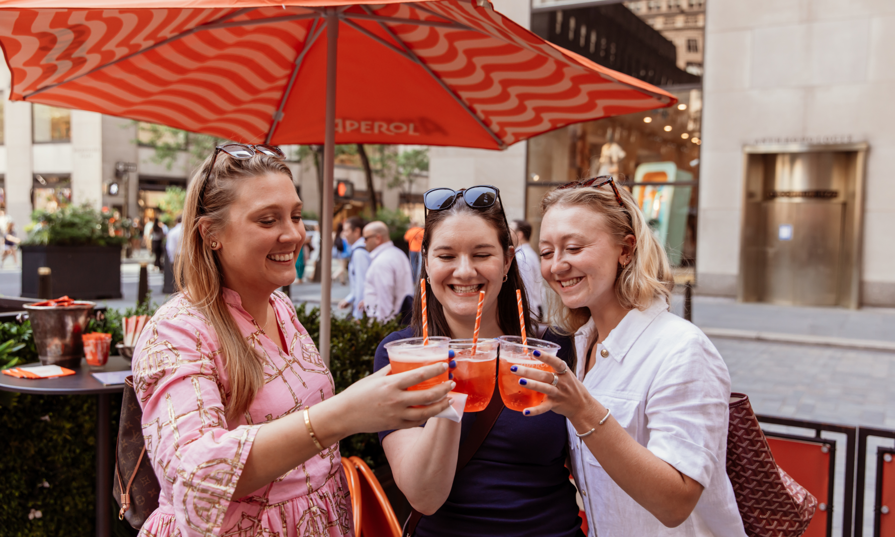 Three women holding Aperol spritzes from Le Rock