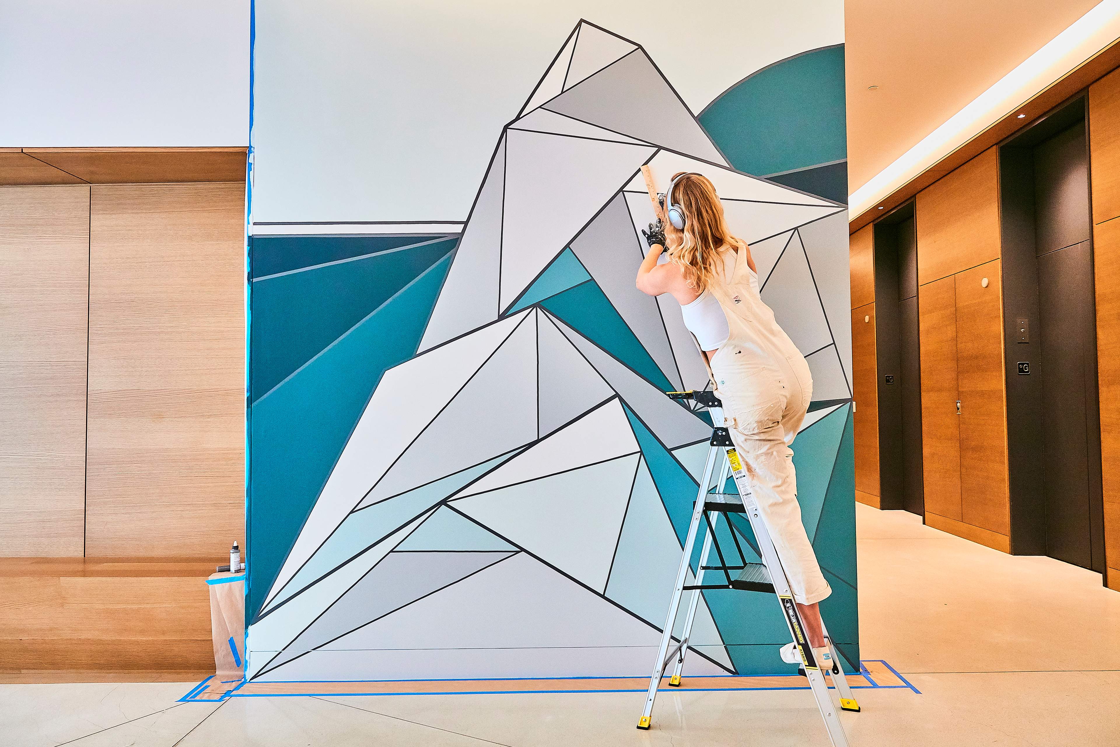 Woman on ladder painting abstract wall design