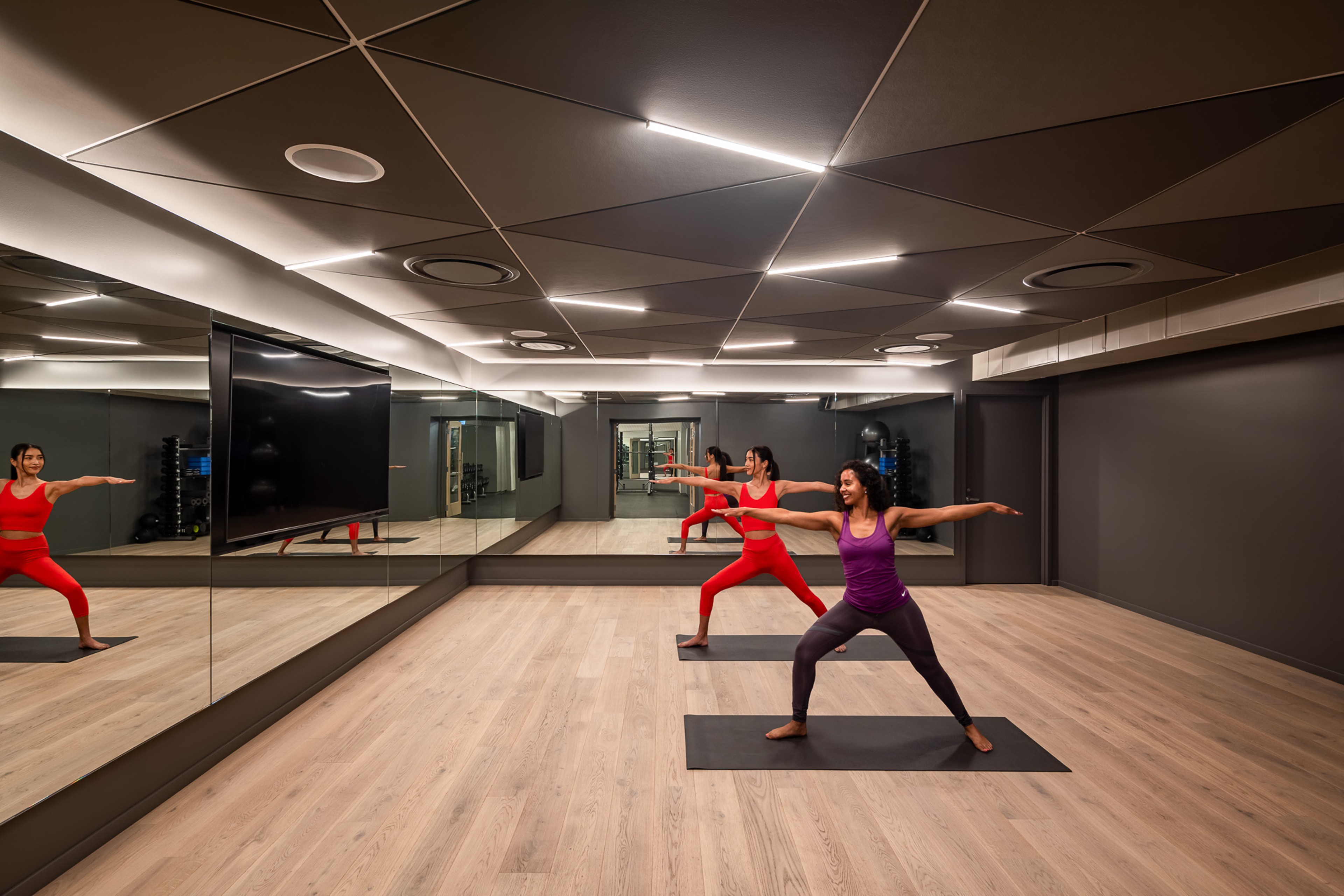 People doing yoga in front of a wall of mirrors
