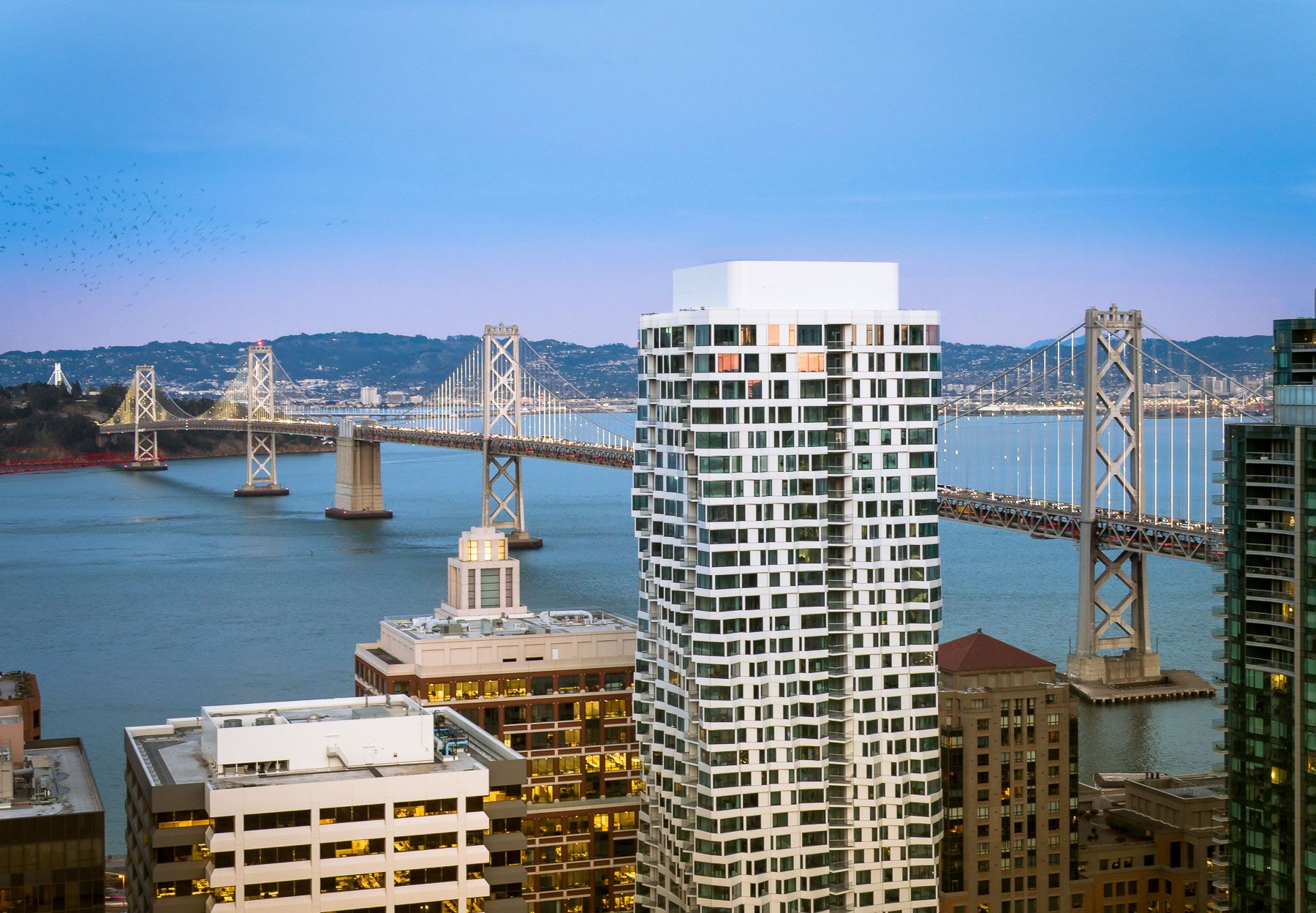 Exterior view of MIRA with Golden Gate Bridget behind it at sunset