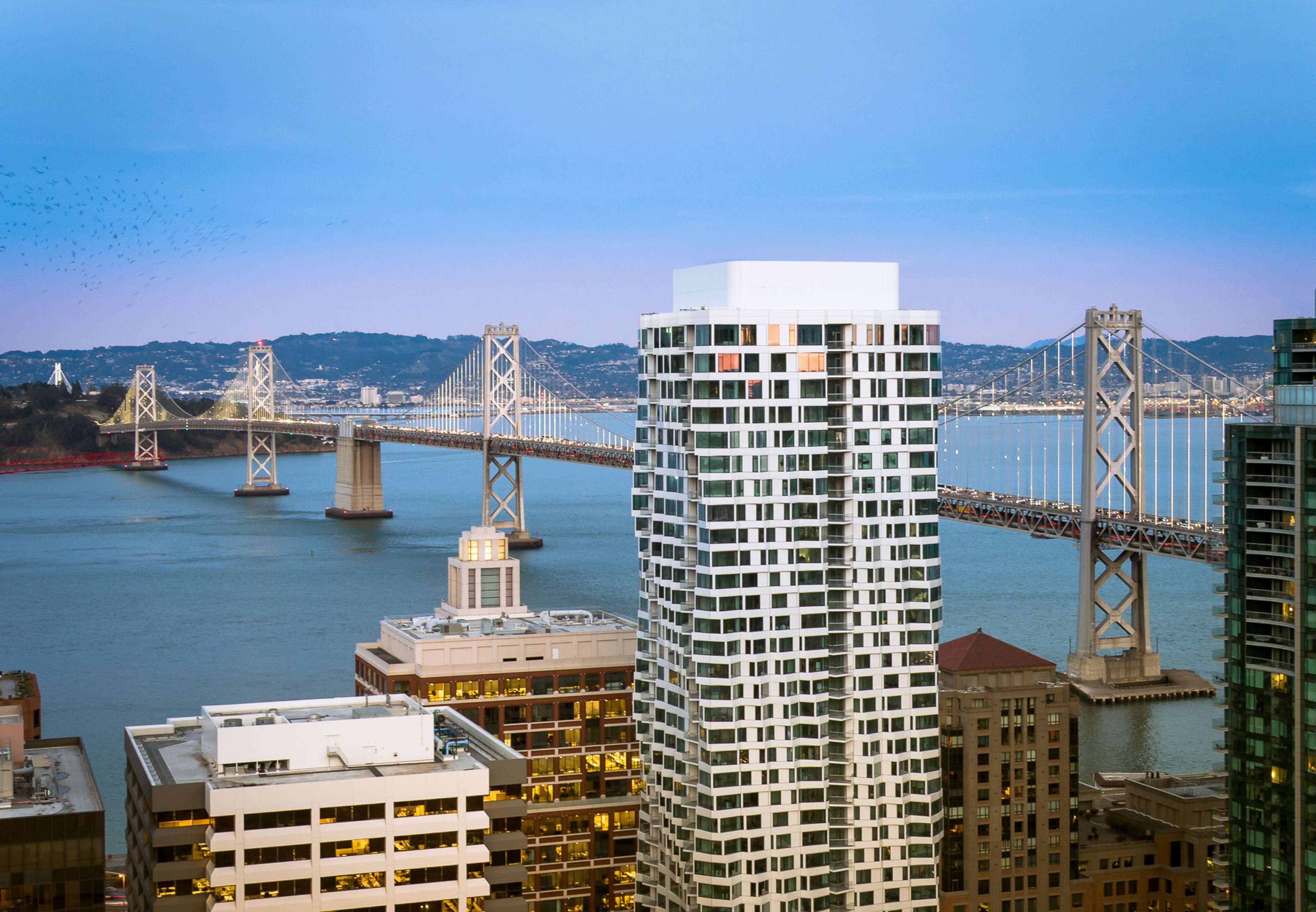 Exterior view of MIRA with Golden Gate Bridget behind it at sunset