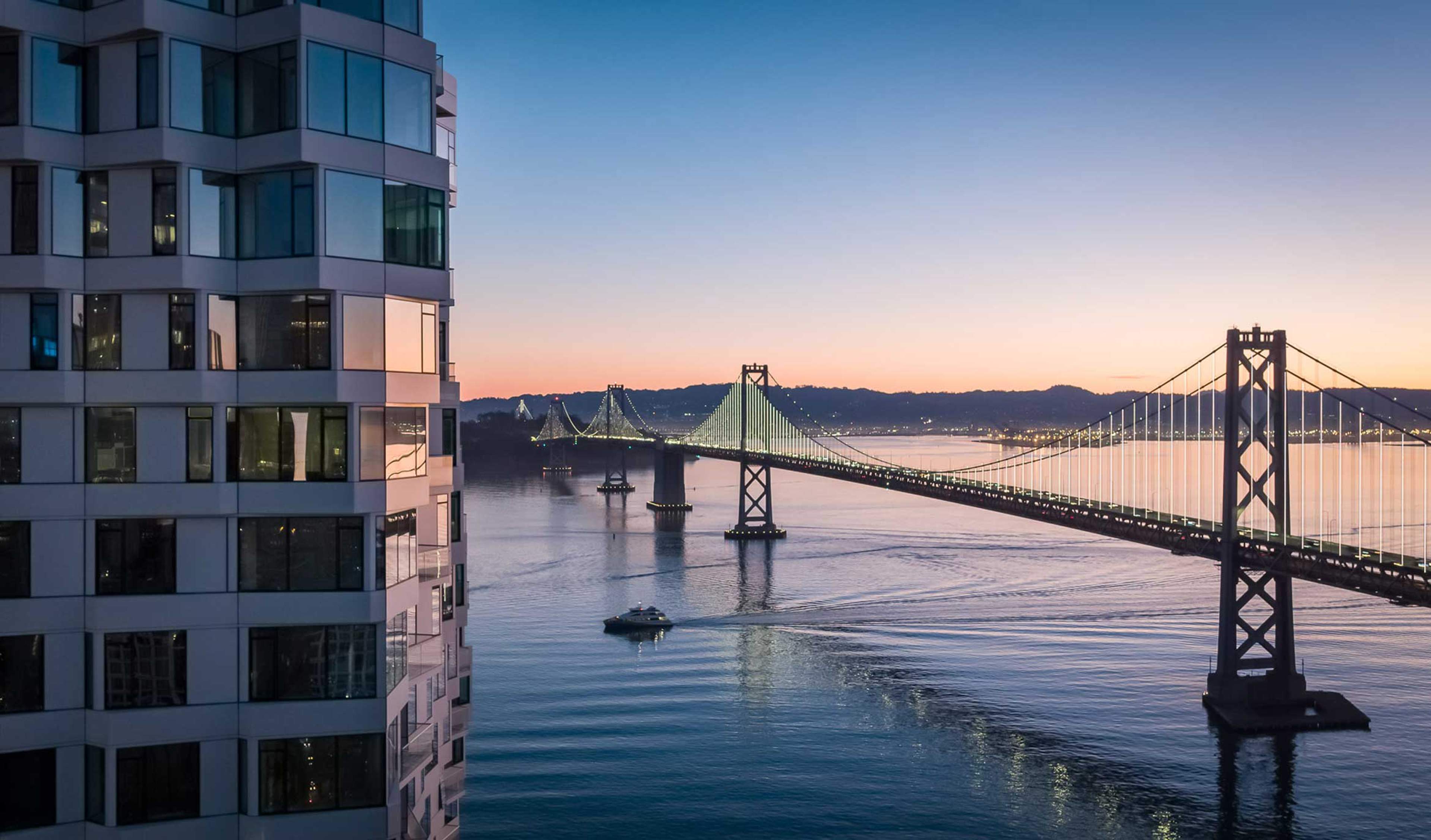 Exterior view of the side of MIRA with Golden Gate Bridget behind it at sunset