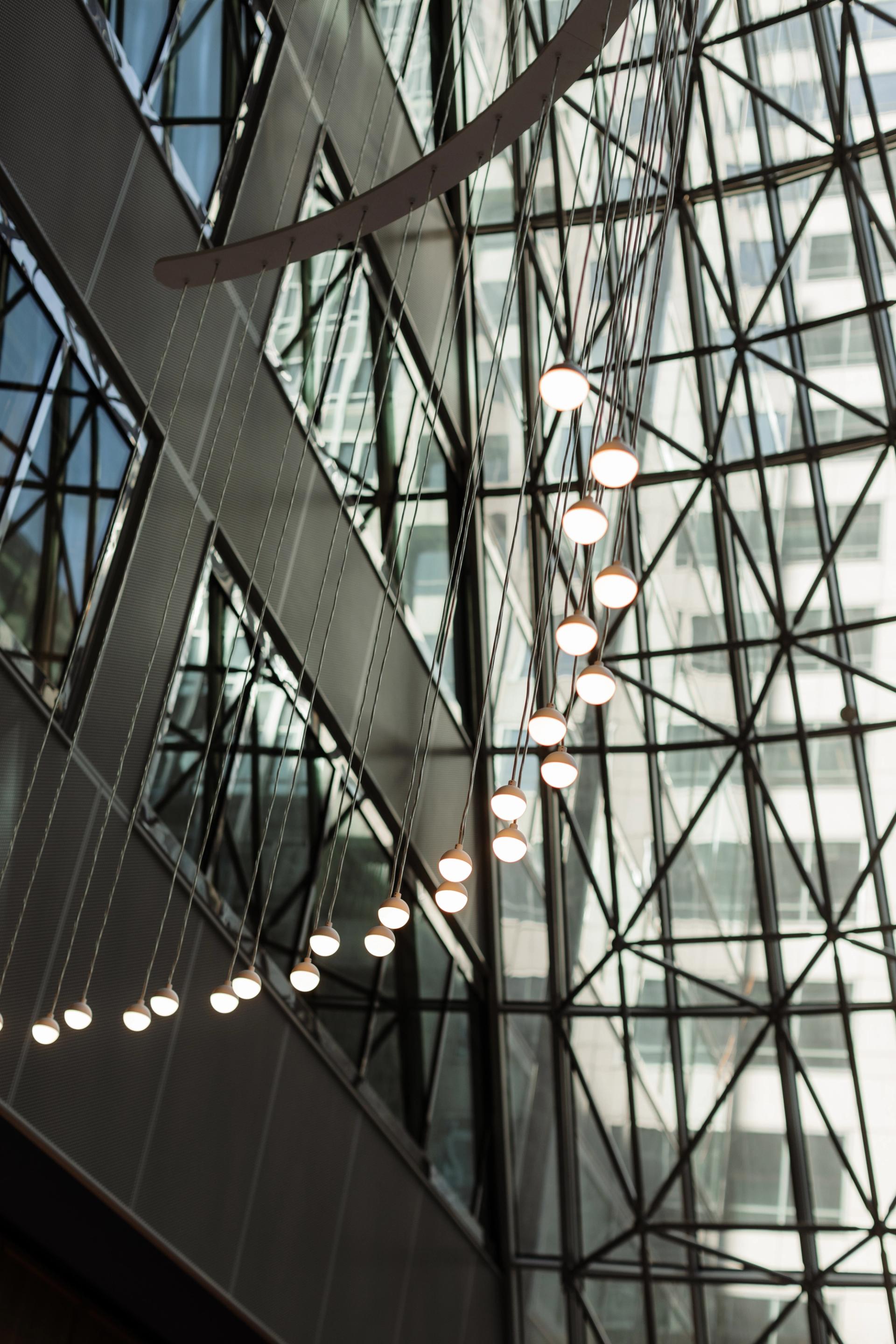 Lobby atrium at 525 West Monroe with a geometric glass ceiling and a cascading row of modern pendant lights suspended on cables.