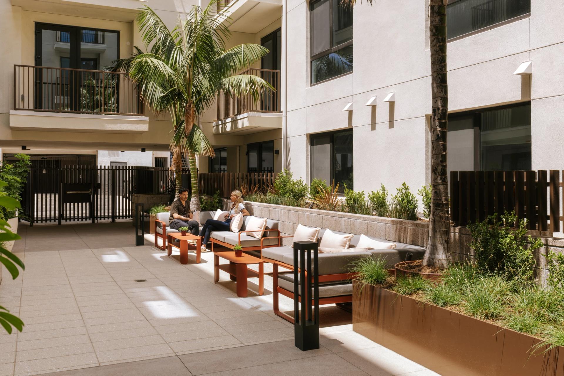 An open air courtyard with lush landscaping and inviting seating designed for gathering, unwinding, and enjoying the outdoors
