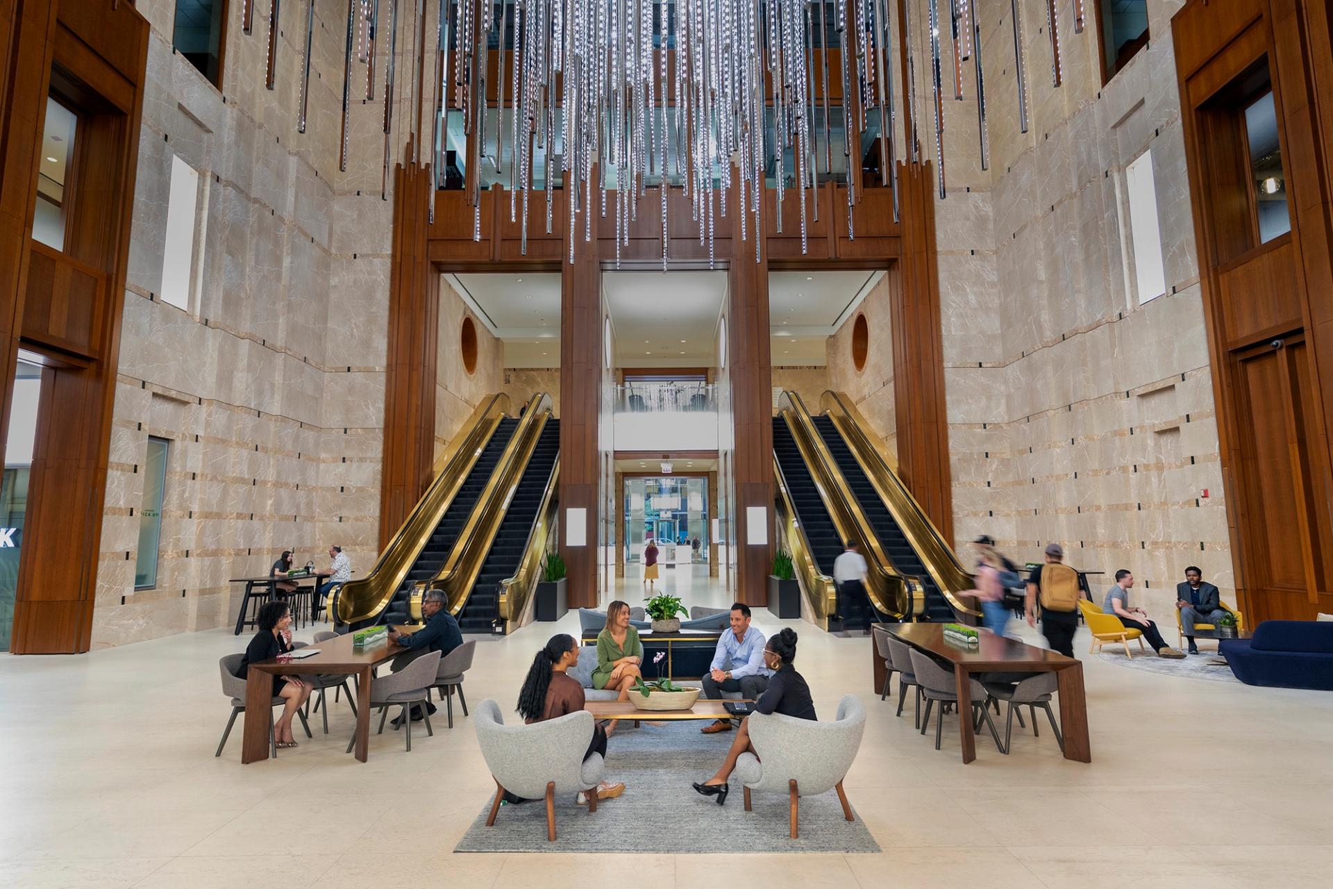 Spacious, modern hotel lobby with a grand chandelier, large windows, and a grand staircase.