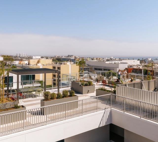 A rooftop designed for gathering, with barbecue stations, comfortable seating, and wide ocean views