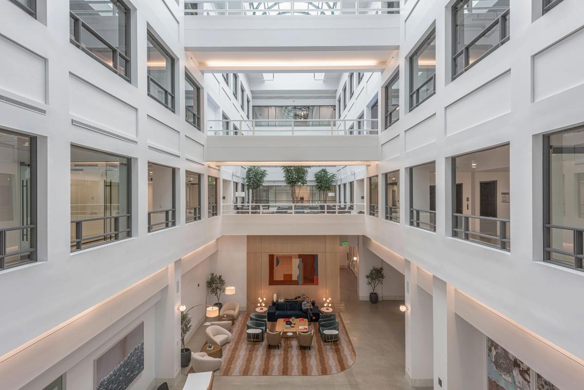 Outdoor seating area under brick archways with people working on laptops and walking.